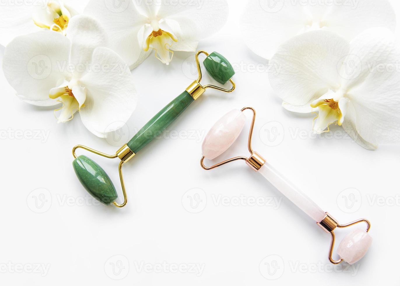 Rolos de jade para massagem facial em fundo branco foto