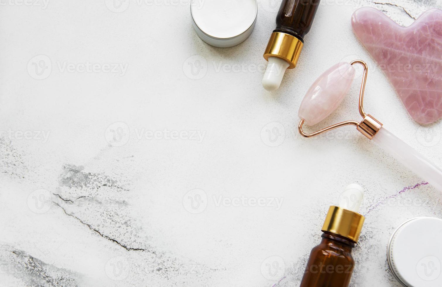 massagem facial rolo jade com produto cosmético em fundo de mármore foto