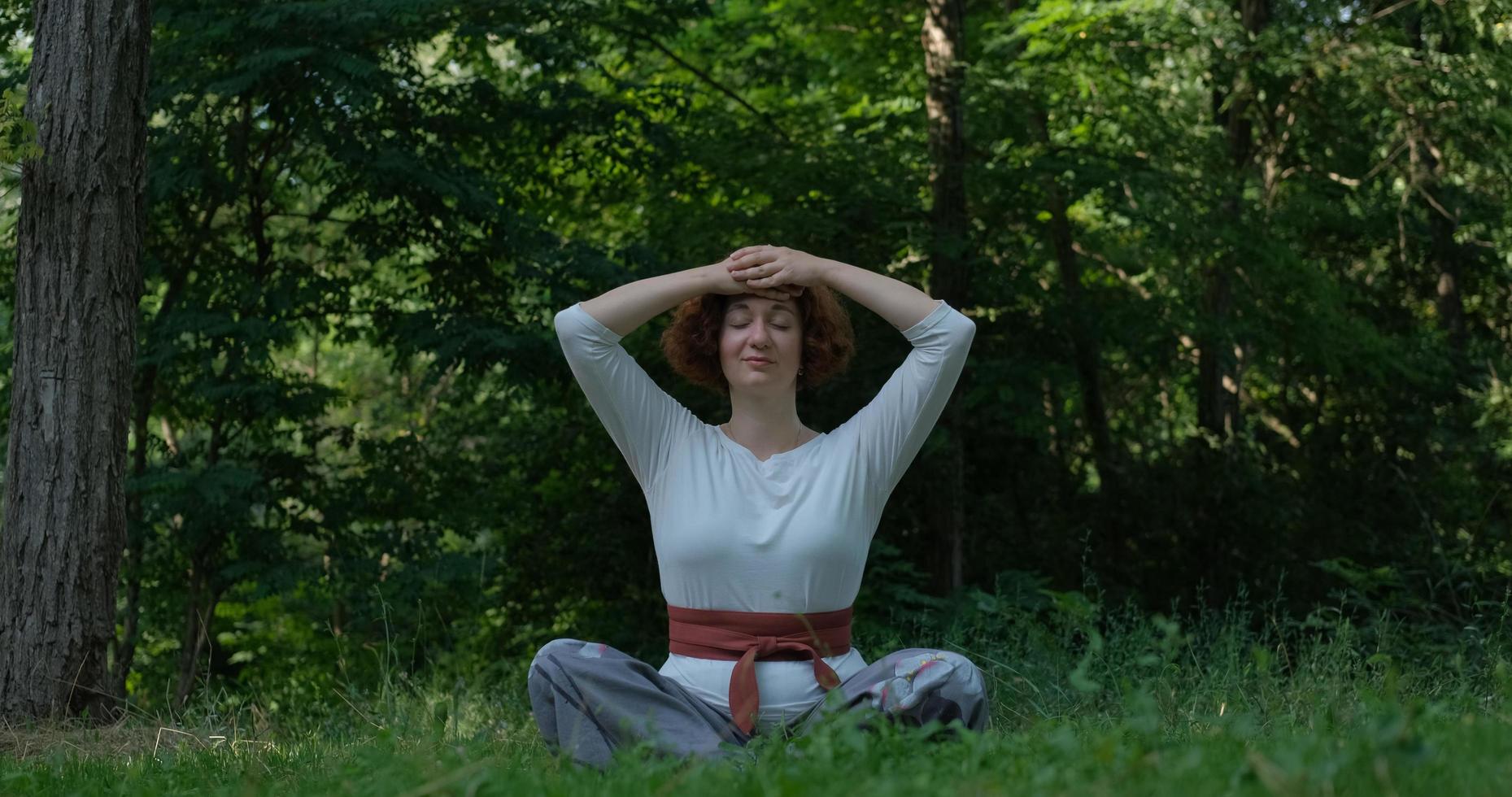 mulher praticando qigong e meditação em parque de verão ou floresta foto