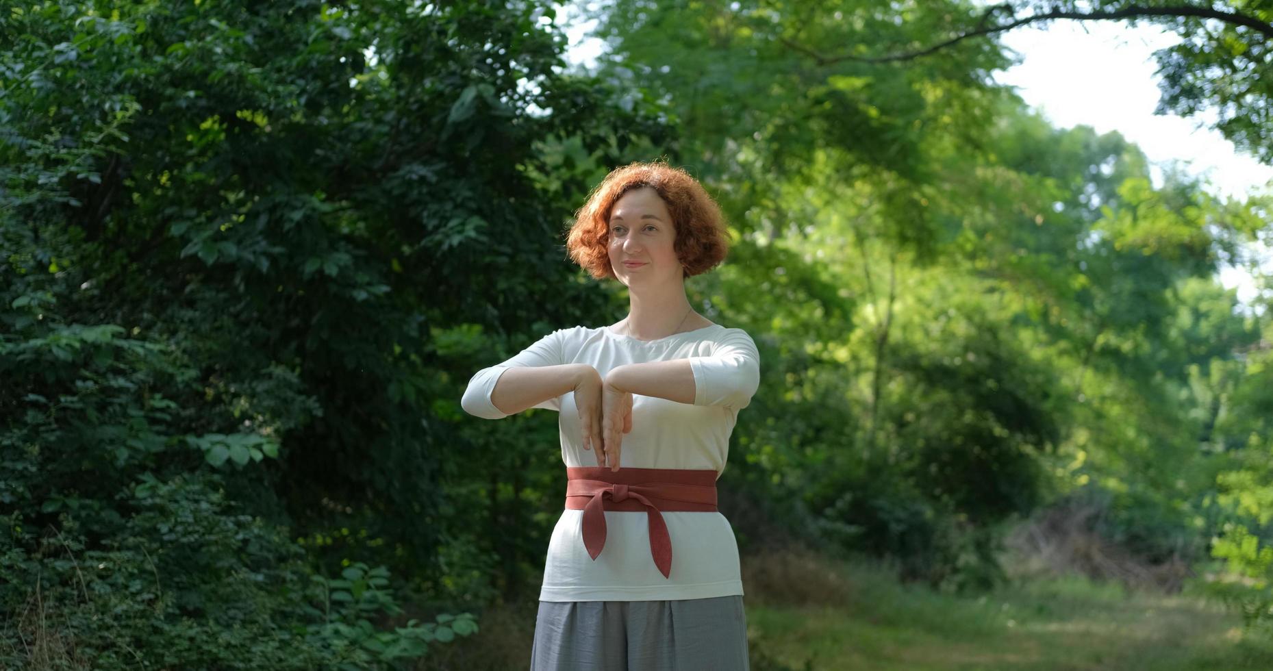 mulher praticando qigong e meditação em parque de verão ou floresta foto