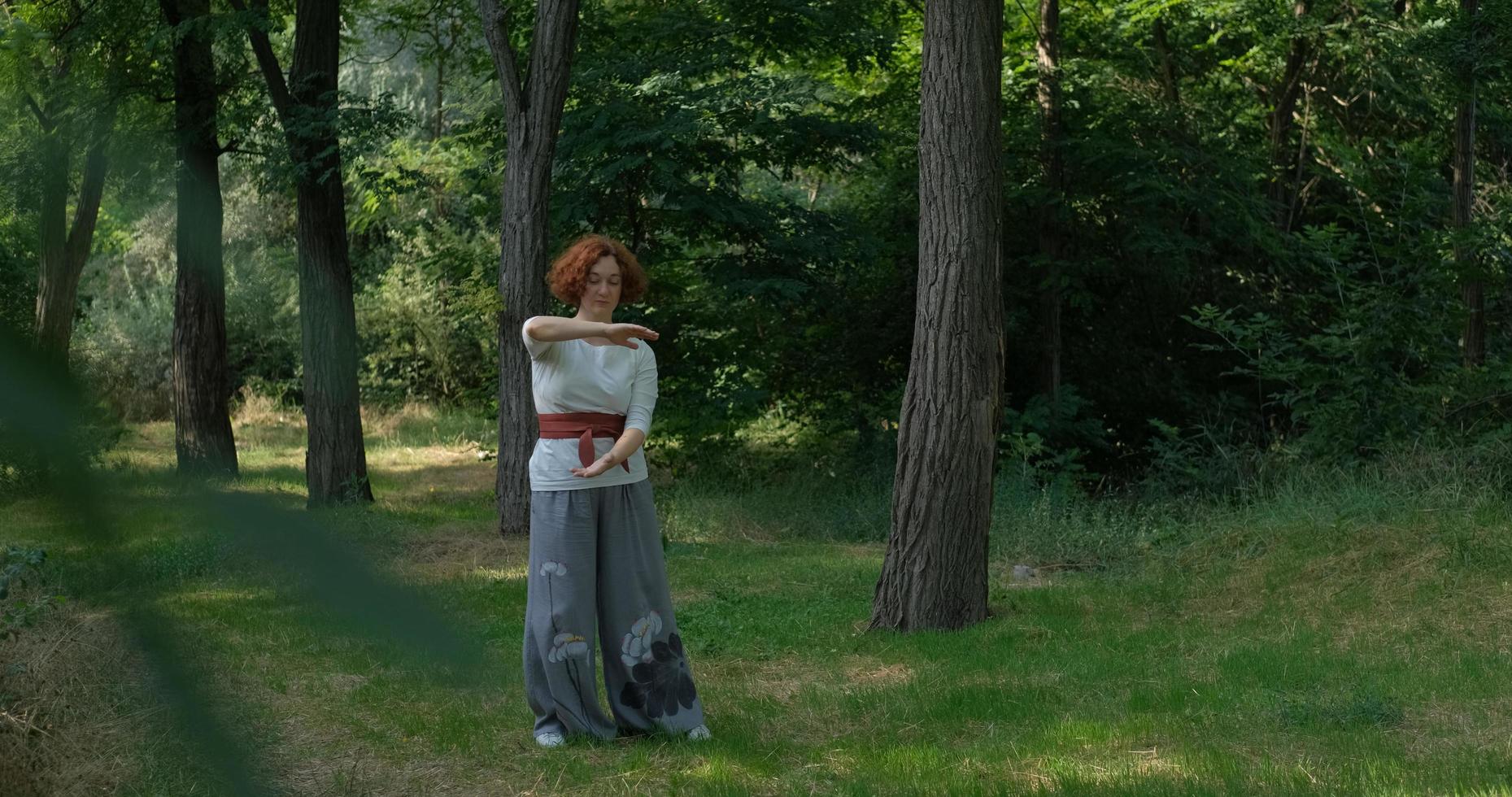 mulher praticando qigong e meditação em parque de verão ou floresta foto