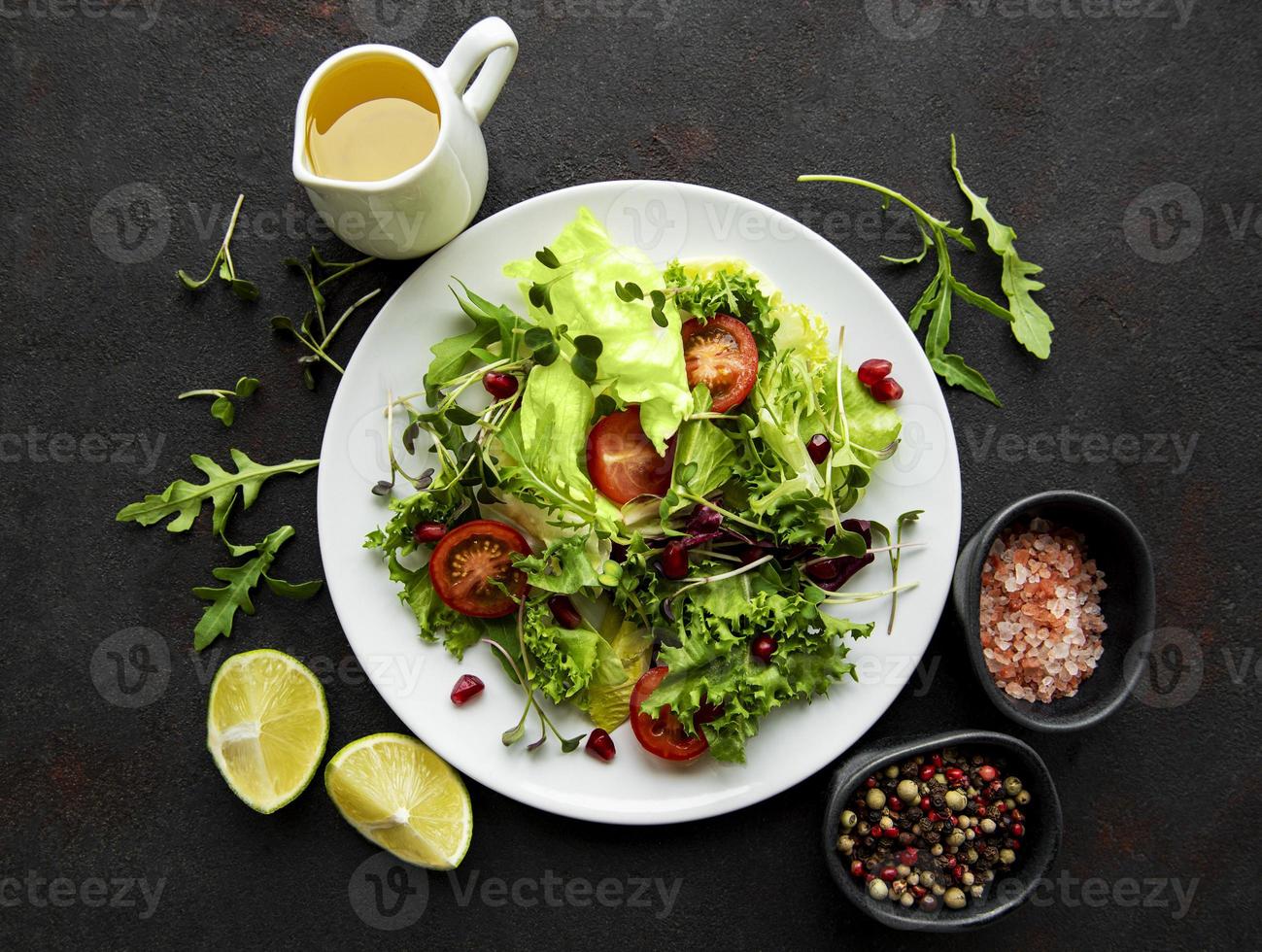 saladeira mista verde fresca com tomates e microgreens em fundo preto de concreto. alimentação saudável, vista superior. foto