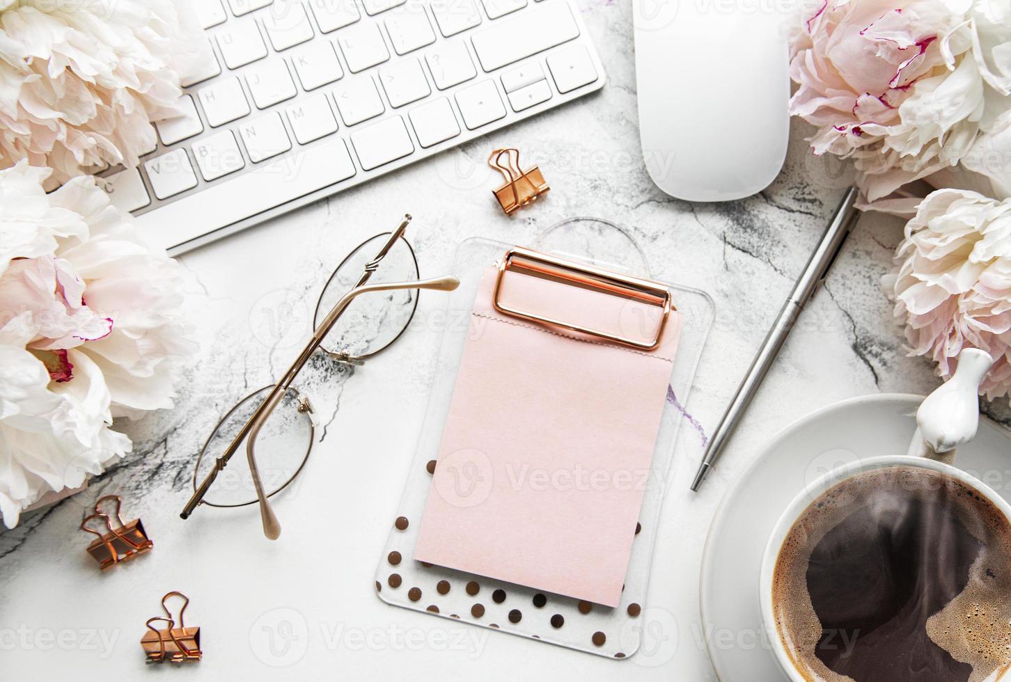 plana leiga vista superior mesa de escritório das mulheres com flores. espaço de trabalho feminino com laptop, peônias de flores, acessórios, caderno, óculos, xícara de café sobre fundo branco. foto