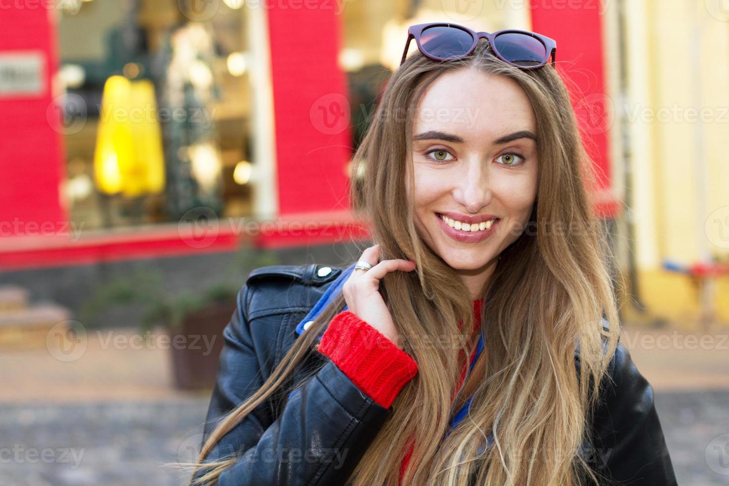 Feche a bela jovem branca de óculos escuros, blusa elegante e jaqueta de couro posando na rua, mulher bonita sexy e elegante sorriso em meio urbano, mulheres brancas em uma cidade grande foto