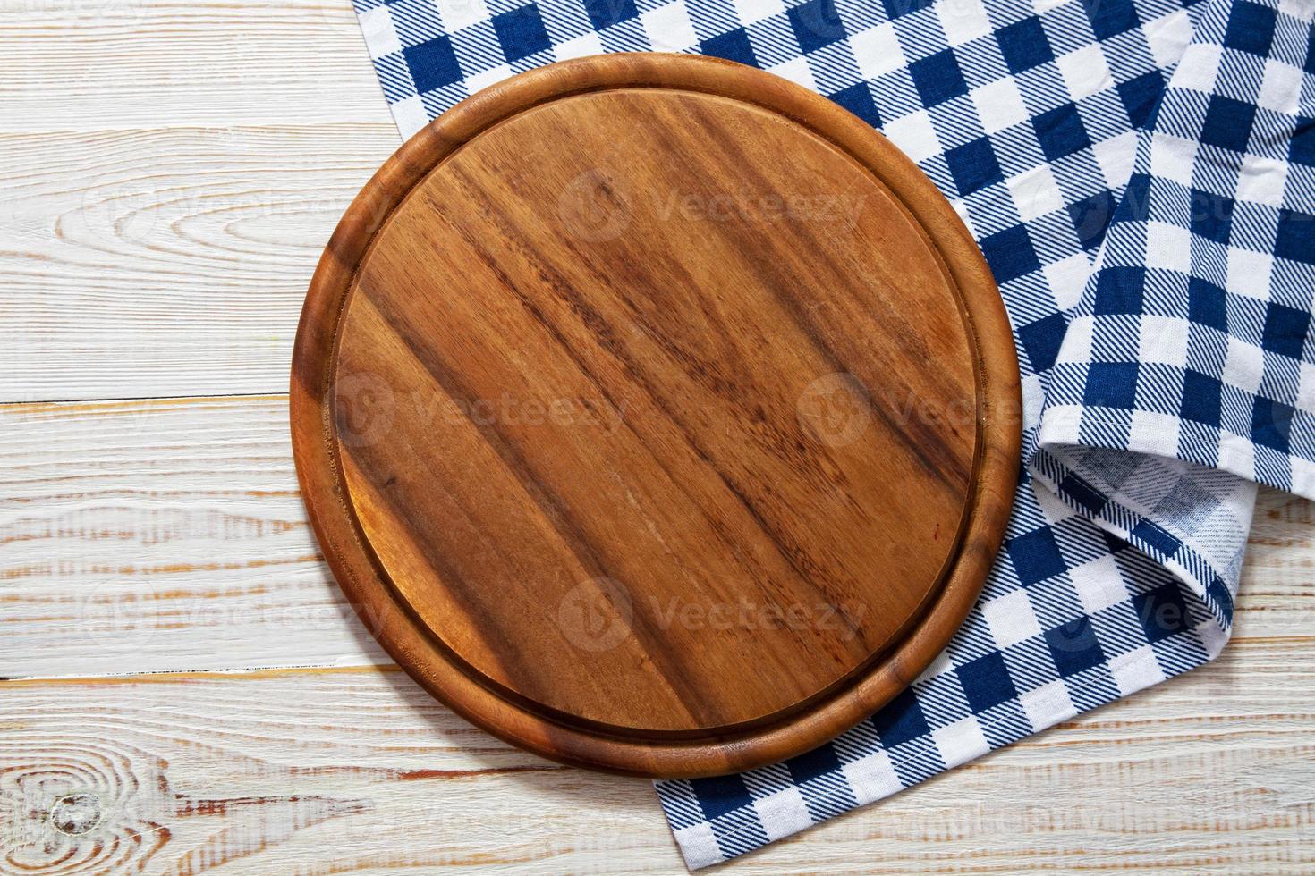 Tábua de madeira vazia e toalha de mesa na mesa - vista superior foto
