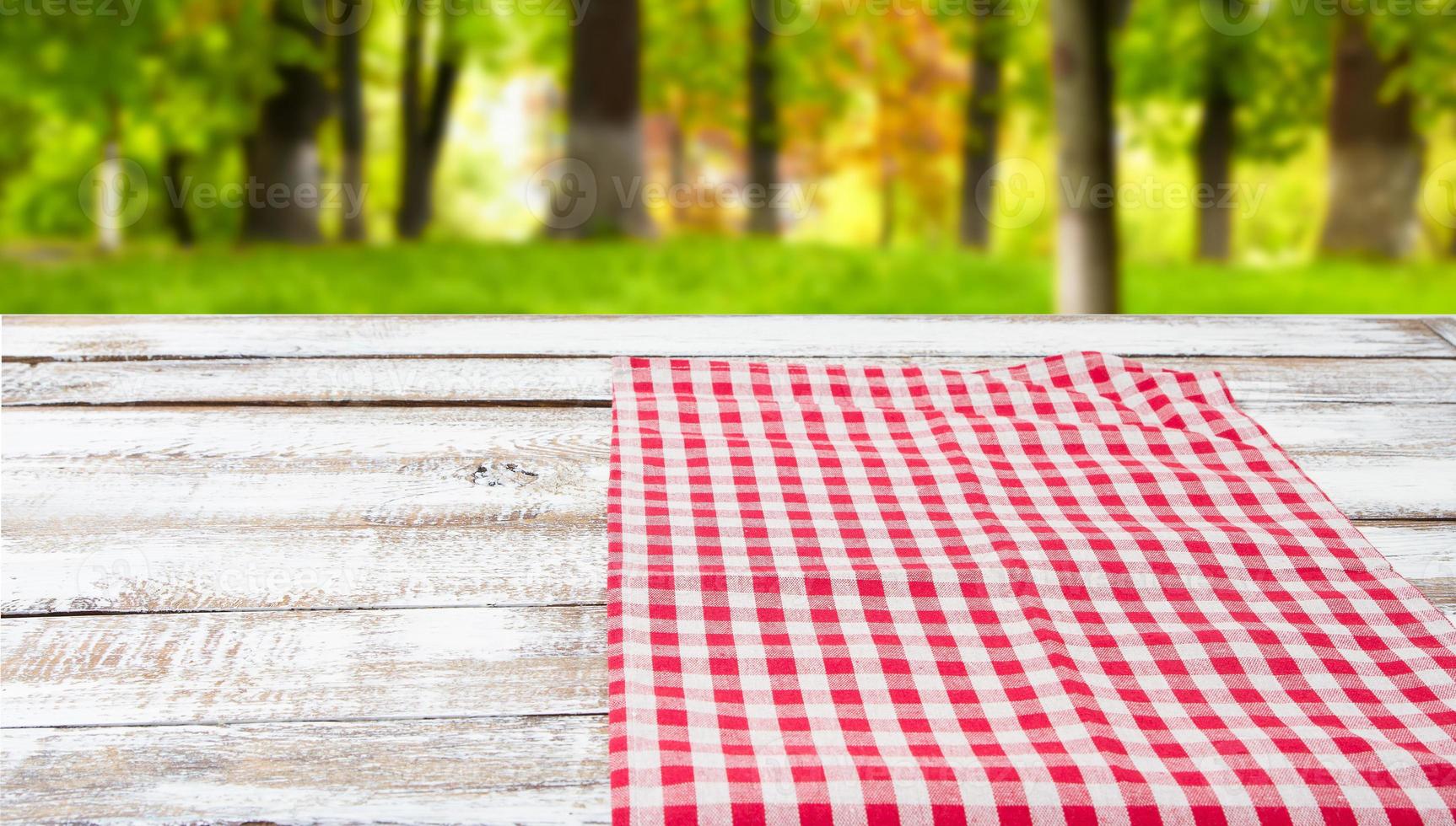 toalha de mesa quadriculada em uma mesa de madeira no fundo da floresta turva foto