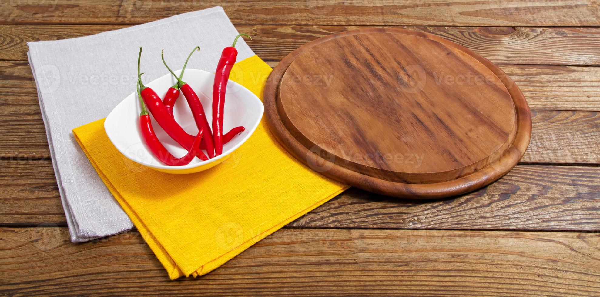 tabuleiro vazio e pimenta vermelha em uma mesa vazia foto