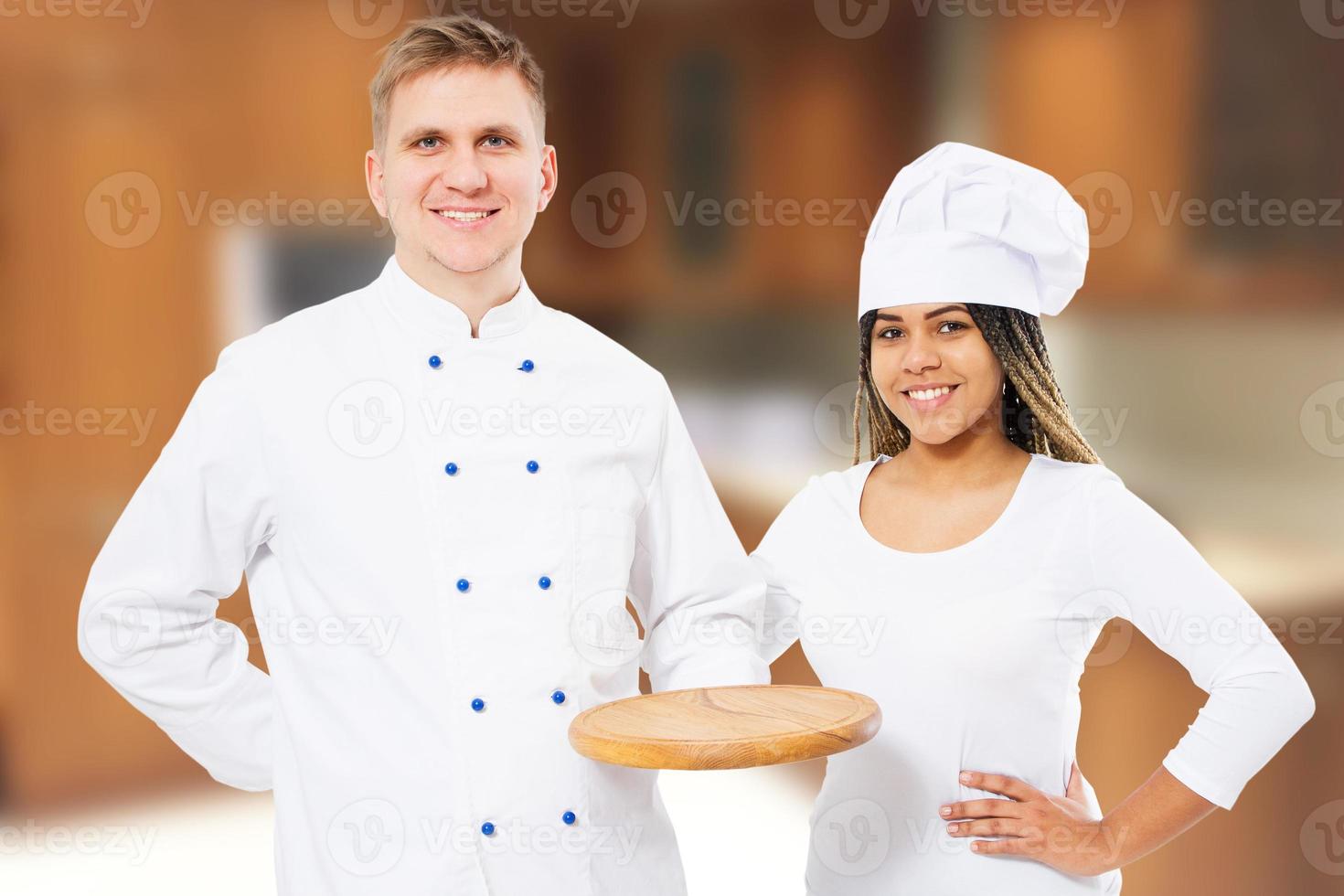 chefs masculinos e femininos com maquete de placa de pizza de madeira vazia na cozinha foto