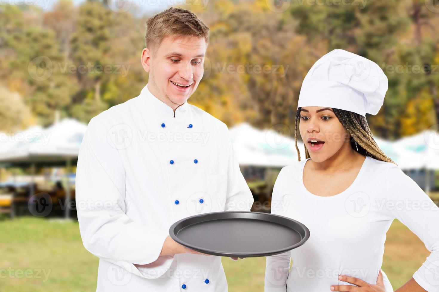 dois chefs emocionais em pé na cozinha com uma simulação de uma bandeja vazia do conceito de maquete de refeição, comida e bebida foto