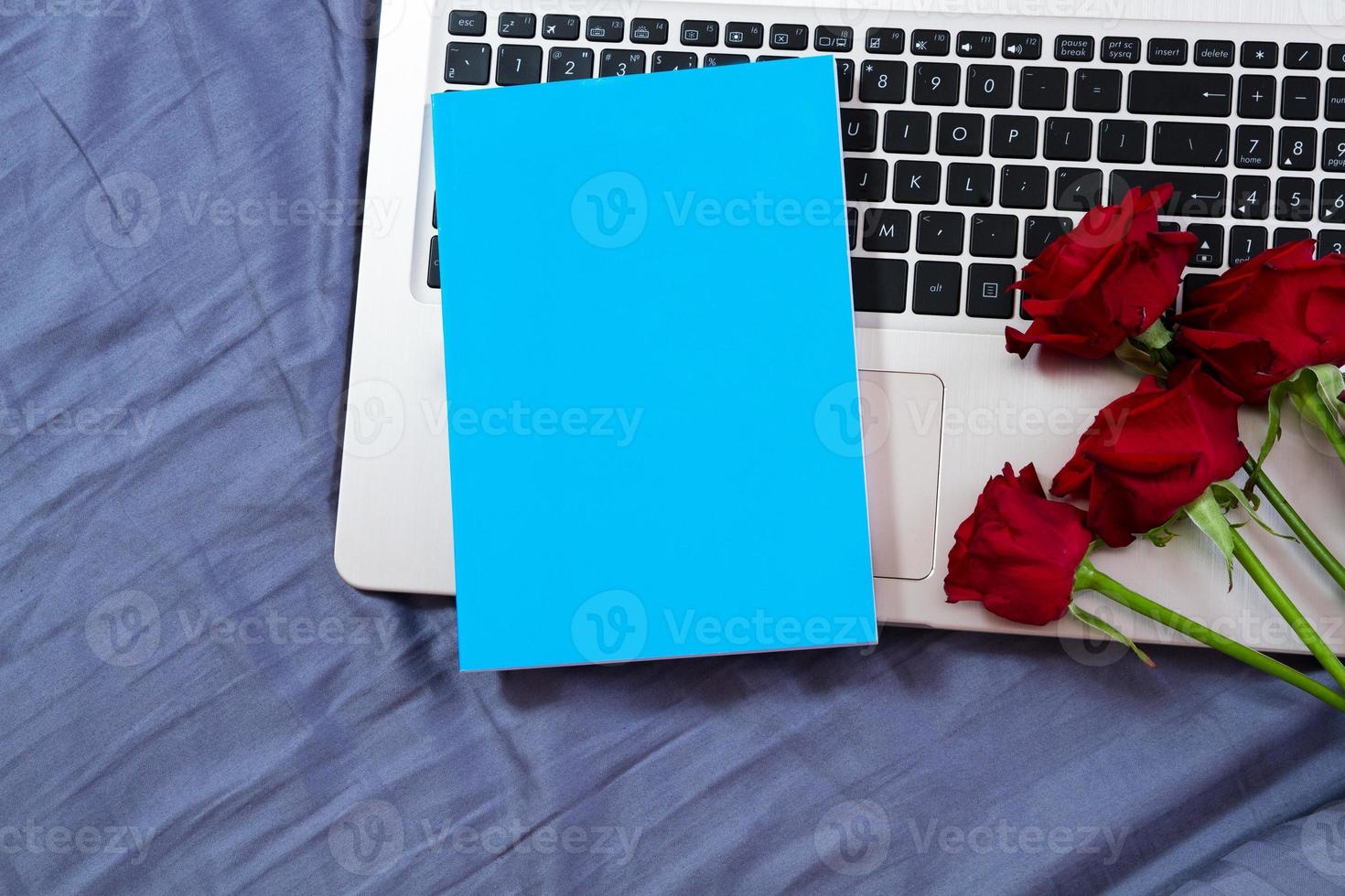 bloco de notas azul simulado no laptop e fundo de flores vermelhas close-up foto