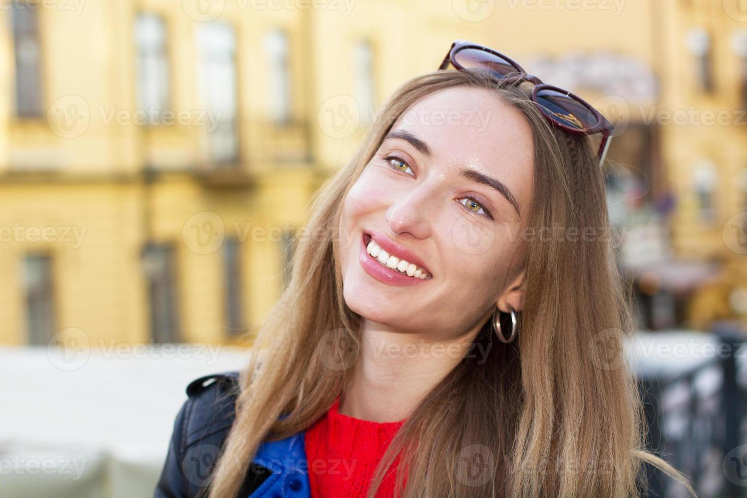 Feche a bela jovem branca de óculos escuros, blusa elegante e jaqueta de couro posando na rua, mulher bonita sexy e elegante sorriso em meio urbano, mulheres brancas em uma cidade grande foto