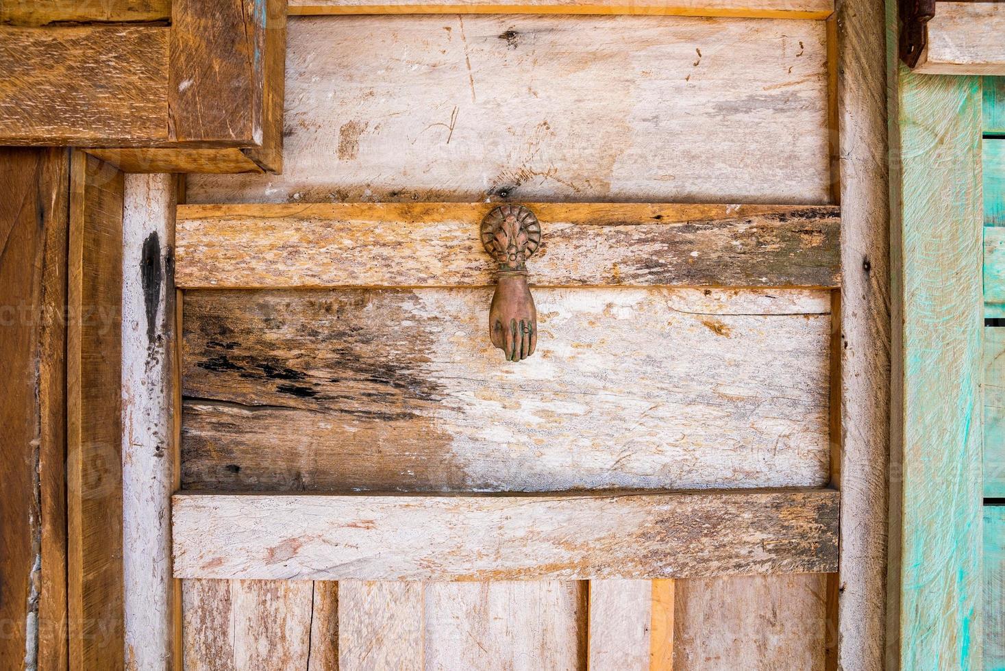 aldrava de ferro enferrujado em forma de mão em porta de madeira estilo vintage retrô foto