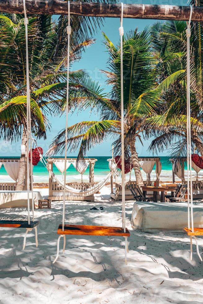 bancos de balanço de madeira em um lindo resort de praia com dossel e rede ao fundo foto