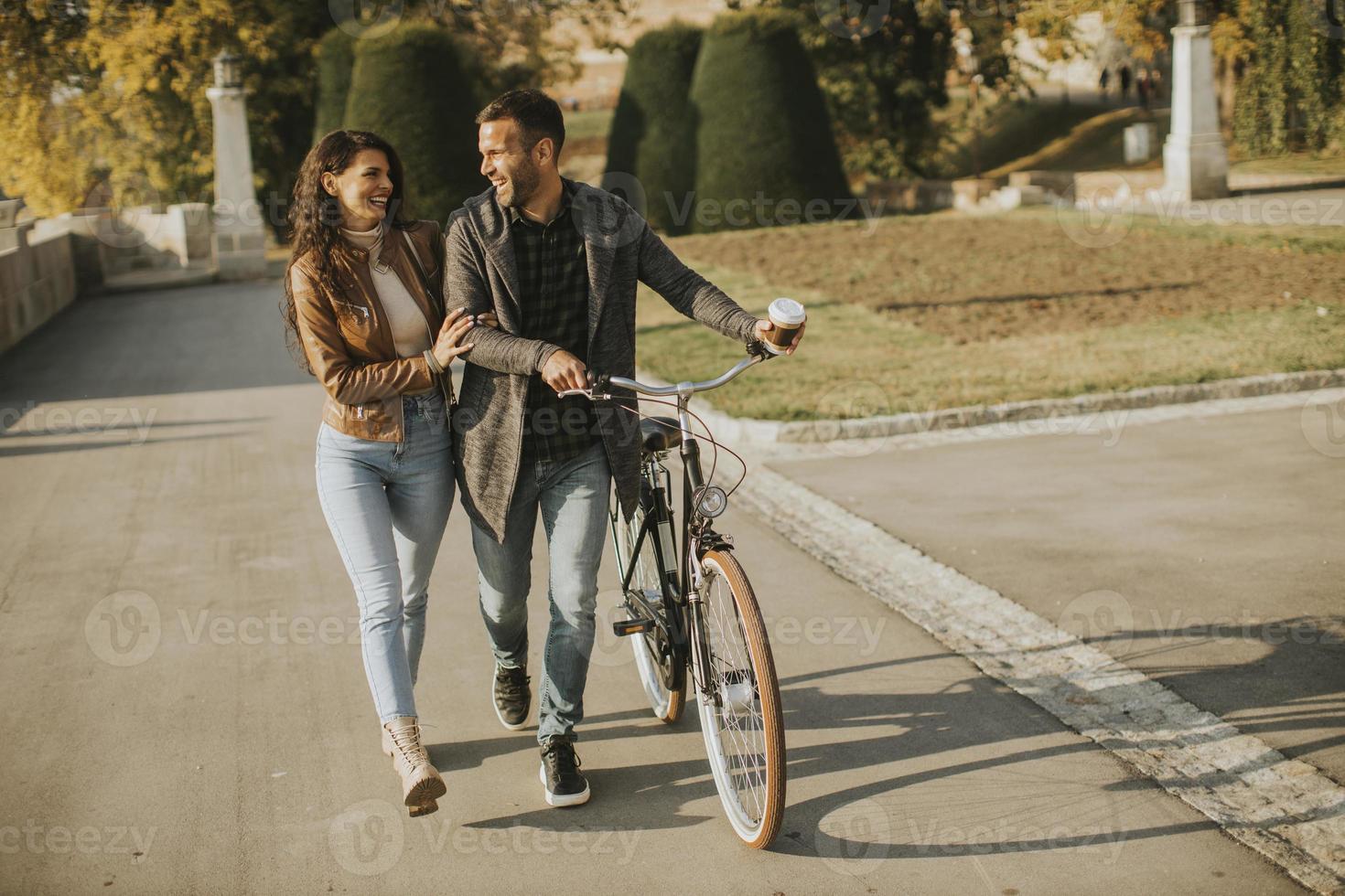 jovem casal caminhando de bicicleta no parque outono foto