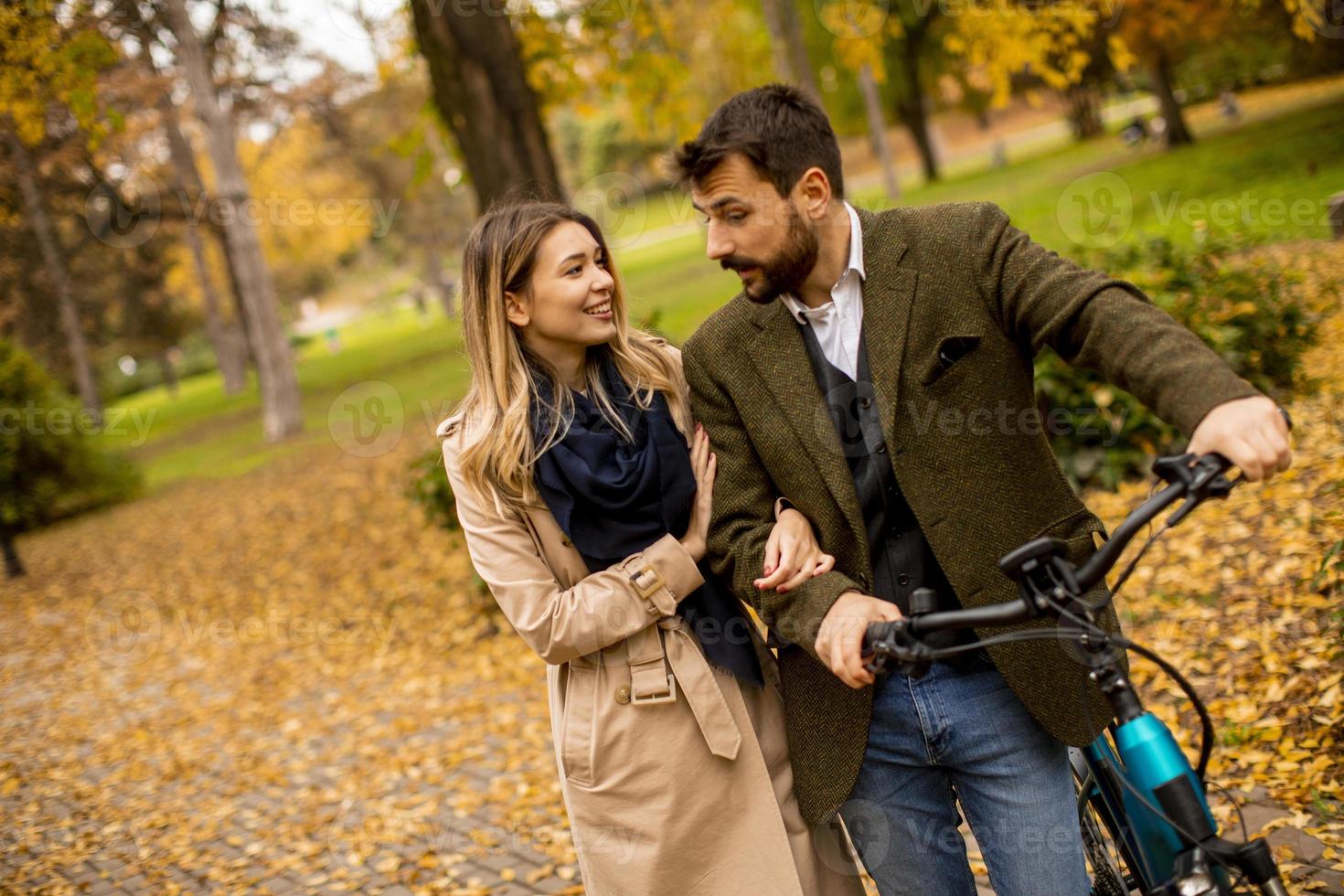 jovem casal no parque outono com bicicleta elétrica foto