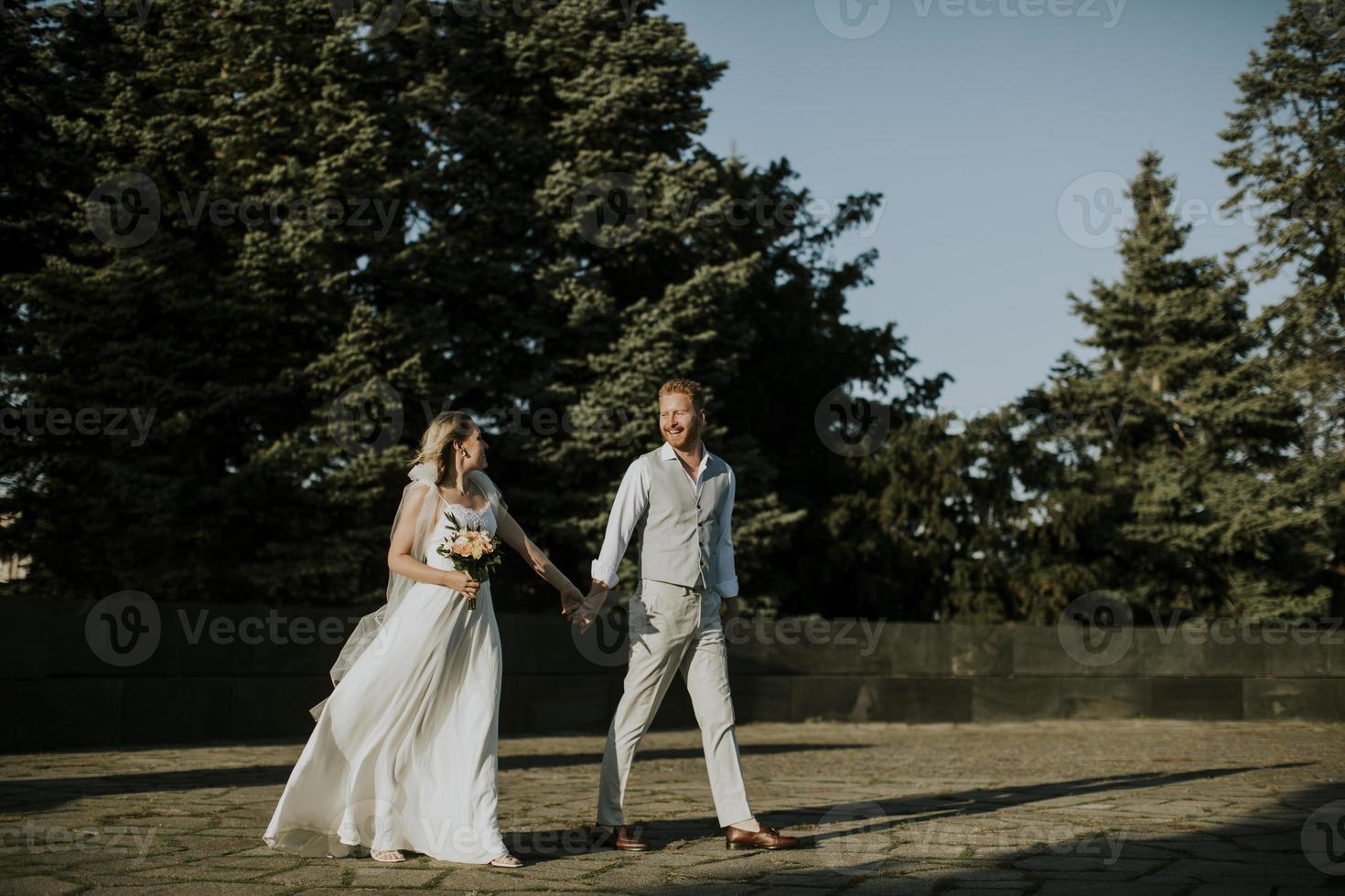 jovem casal recém-casado caminhando no parque foto