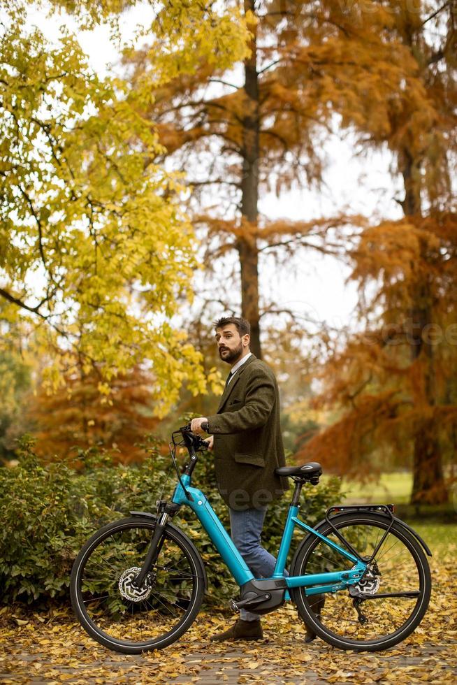 jovem com bicicleta elétrica no parque outono foto