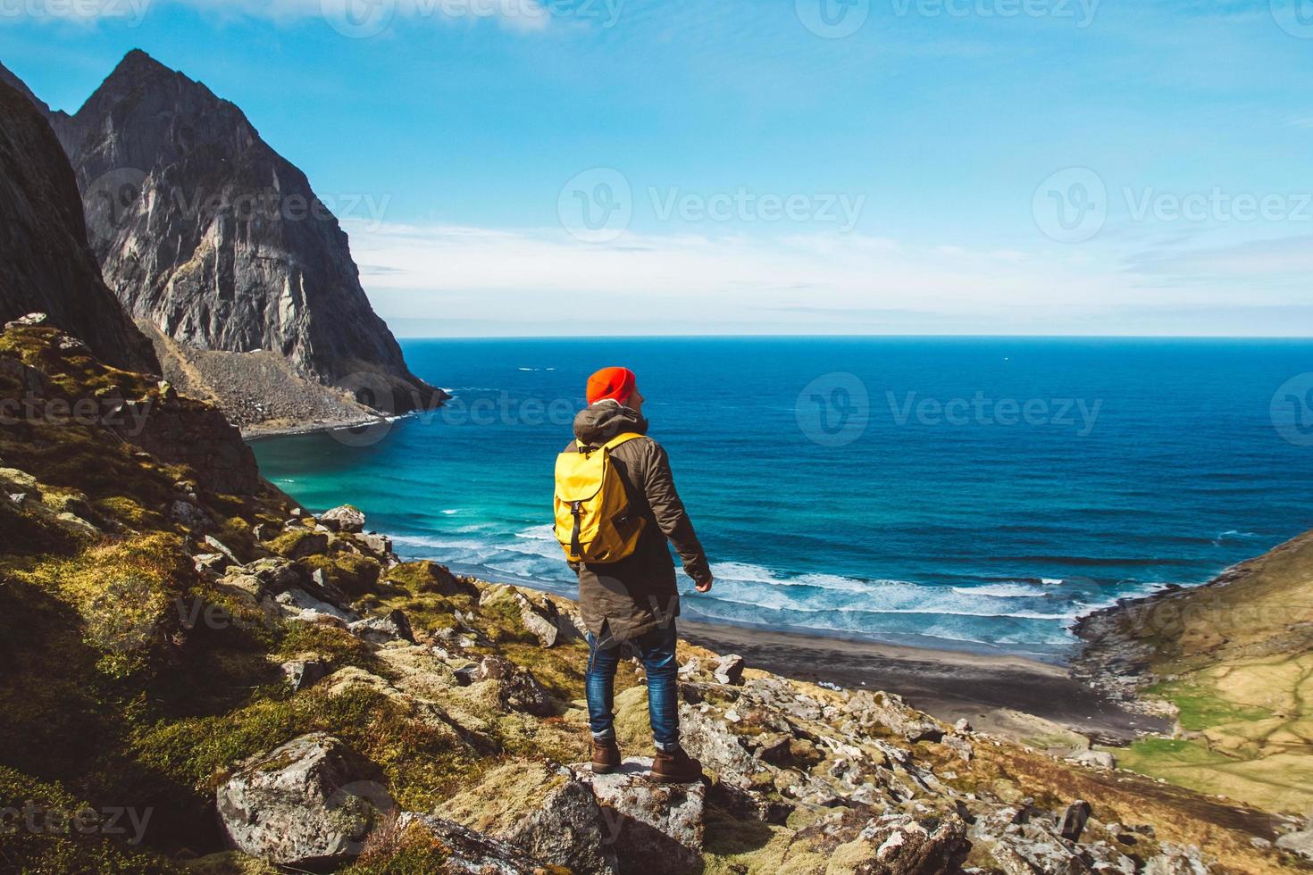 homem viajante fica na beira do penhasco, no fundo das montanhas, rochas e mar. lugar para texto ou publicidade foto