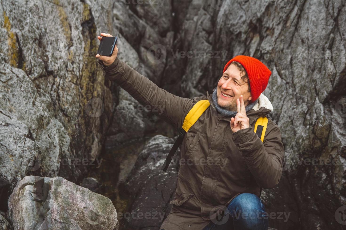 homem viajante tirando auto-retrato com um smartphone no contexto de montanhas e rochas. lugar para texto ou publicidade foto