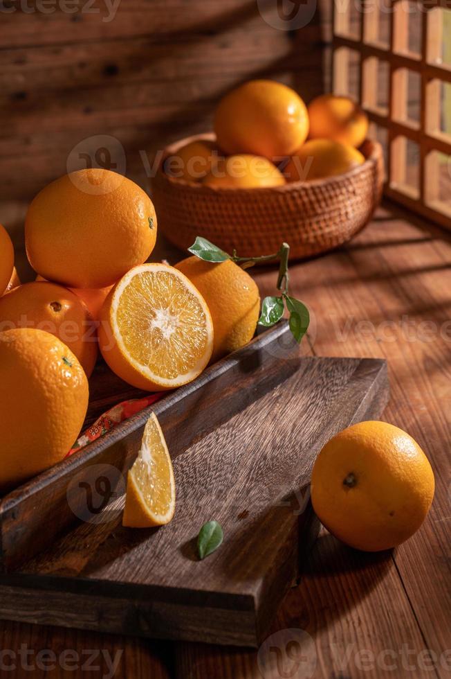 sob a luz fraca, as laranjas no prato estão na mesa de madeira, como pinturas a óleo foto