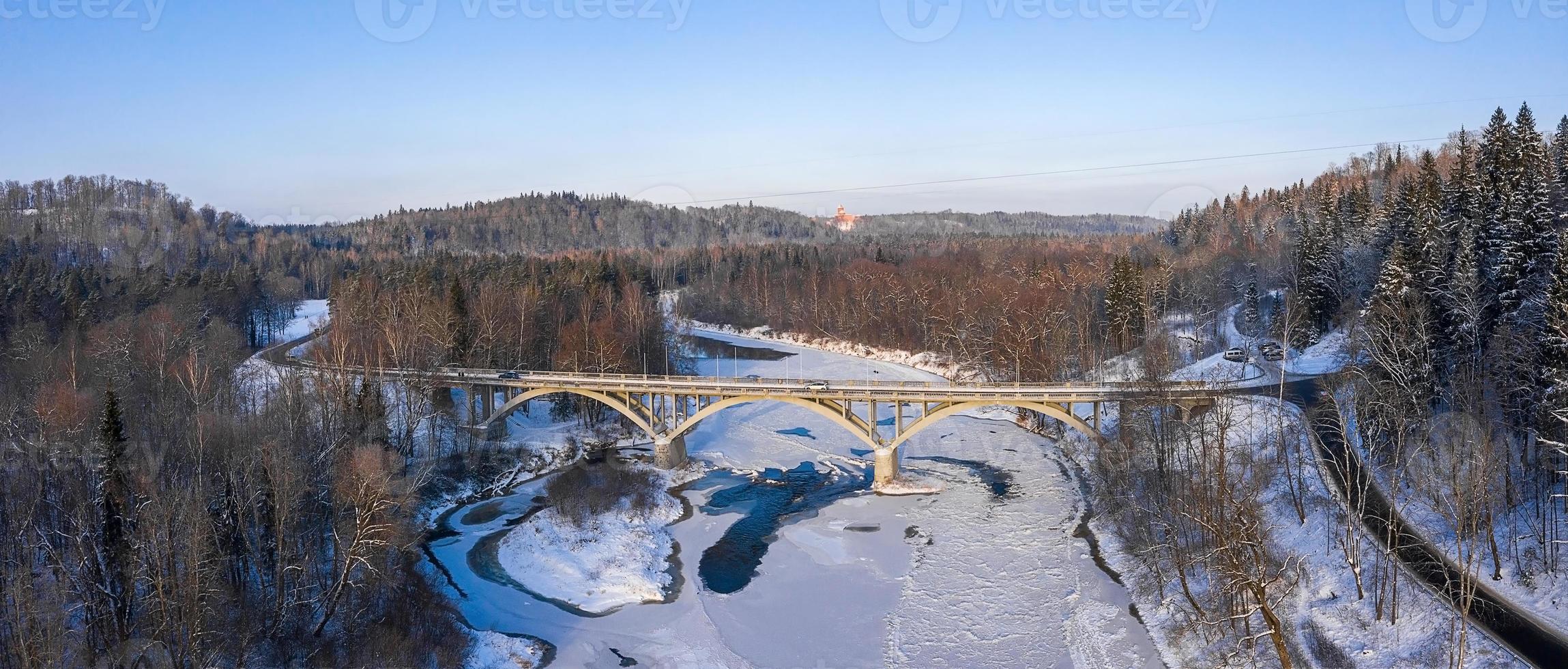 temporada de inverno vista aérea de cima para baixo de uma ponte com uma estrada de linha reta sobre o rio foto