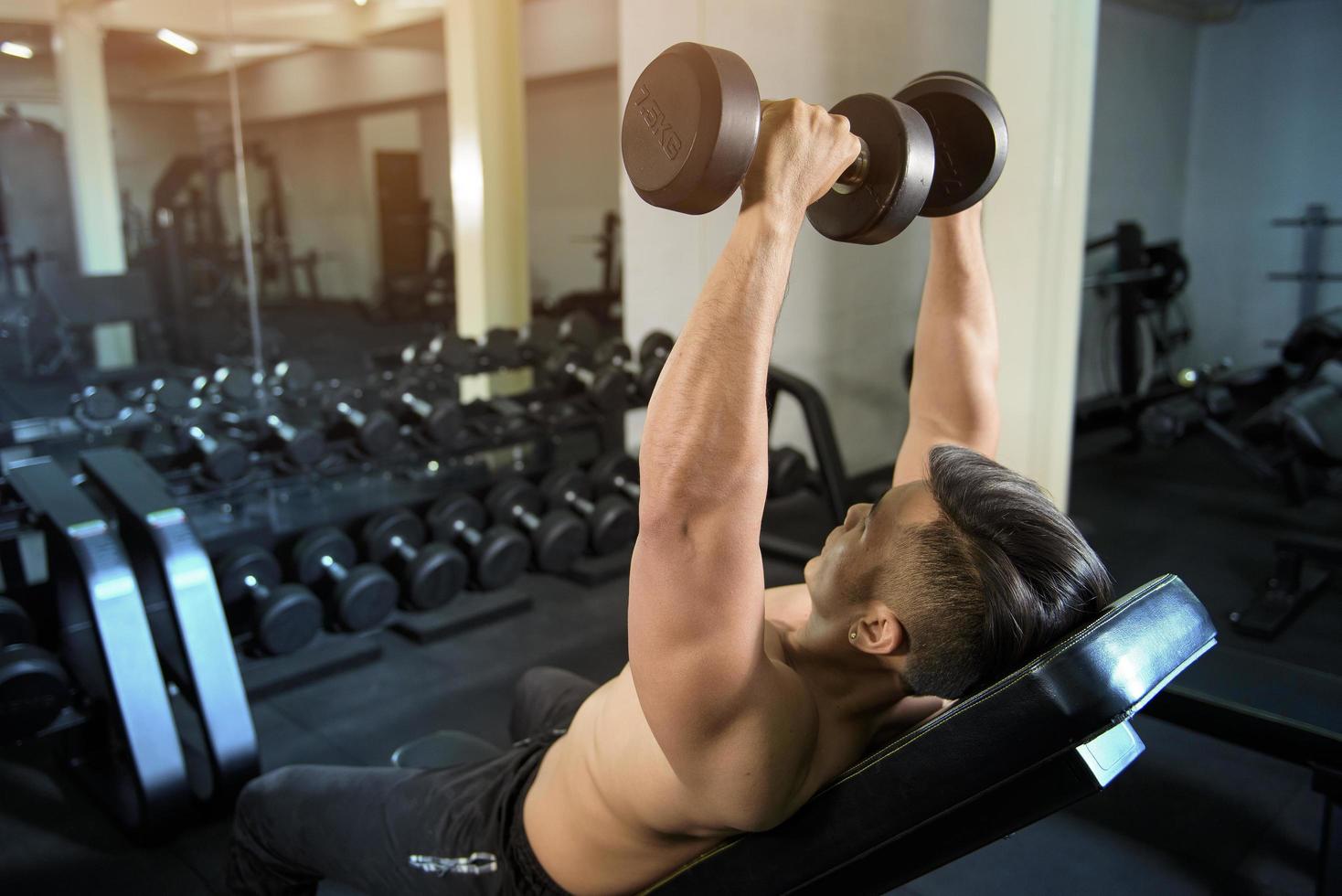 fisiculturista de homem de aptidão muscular é treino com halteres no ginásio foto