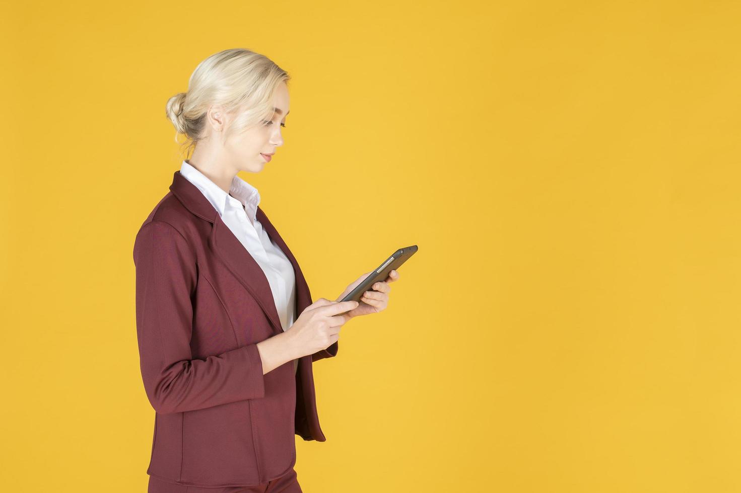 mulher de negócios está usando tablet em fundo amarelo de estúdio foto