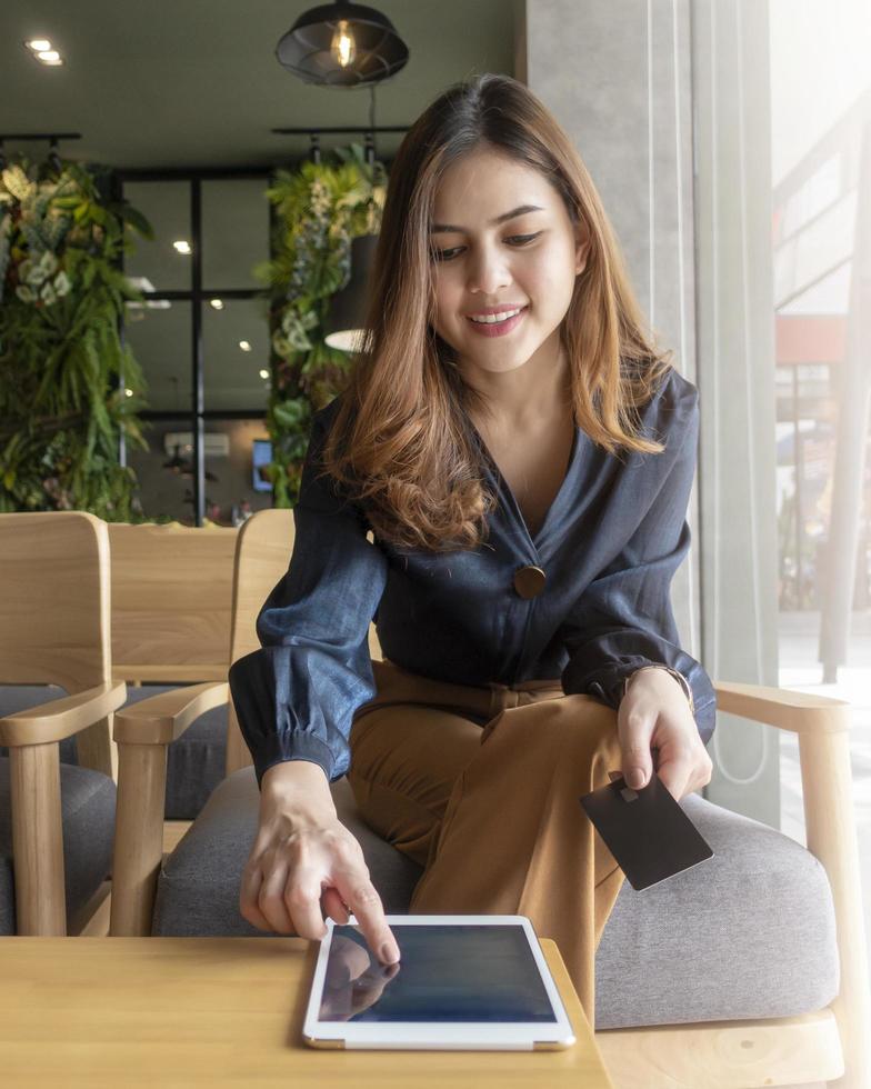 linda mulher está trabalhando com tablet na cafeteria foto