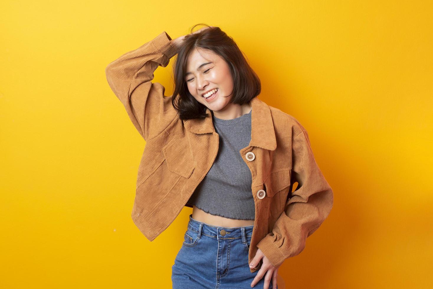 bela mulher asiática estudante universitário feliz em fundo amarelo foto