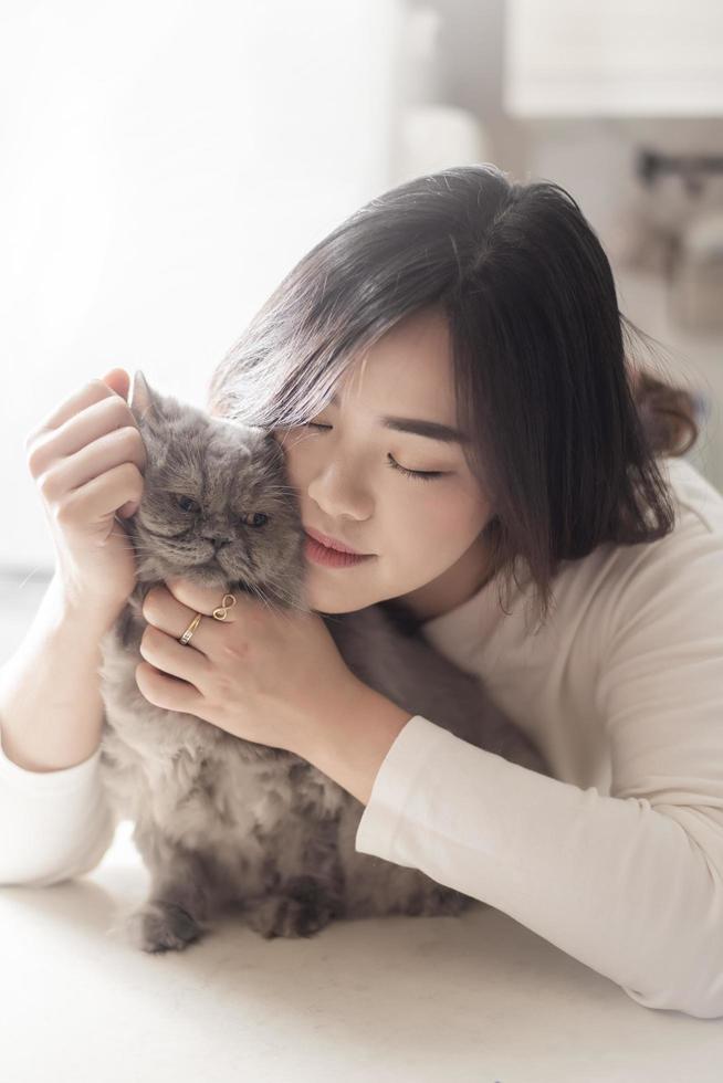 linda mulher amante de gatos asiáticos está brincando com gato em seu quarto foto