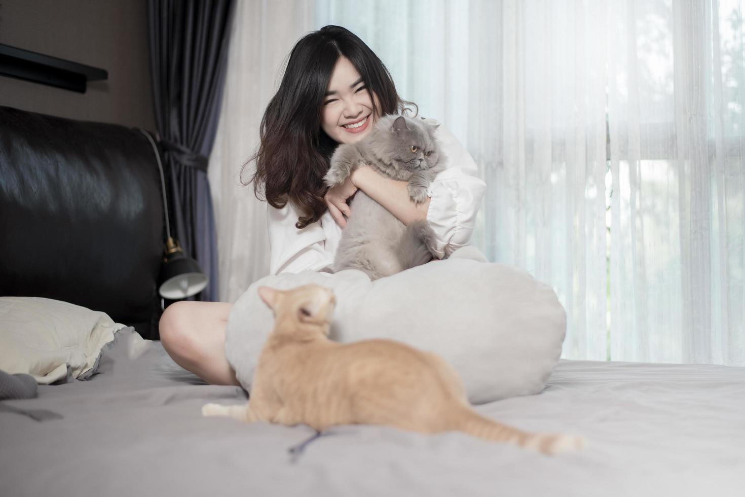 linda mulher amante de gatos asiáticos está brincando com gato em seu quarto foto
