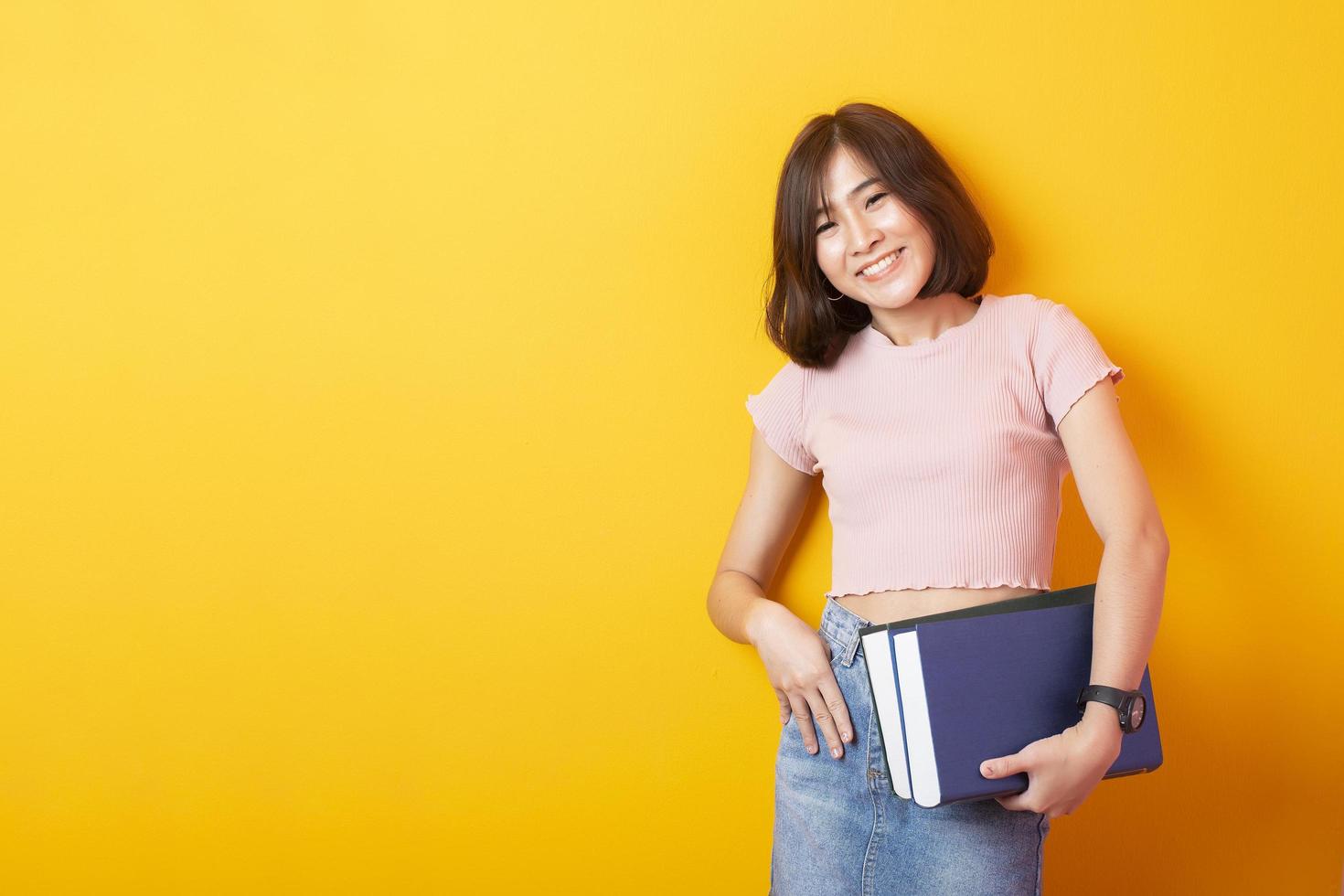 bela mulher asiática estudante universitário feliz em fundo amarelo foto