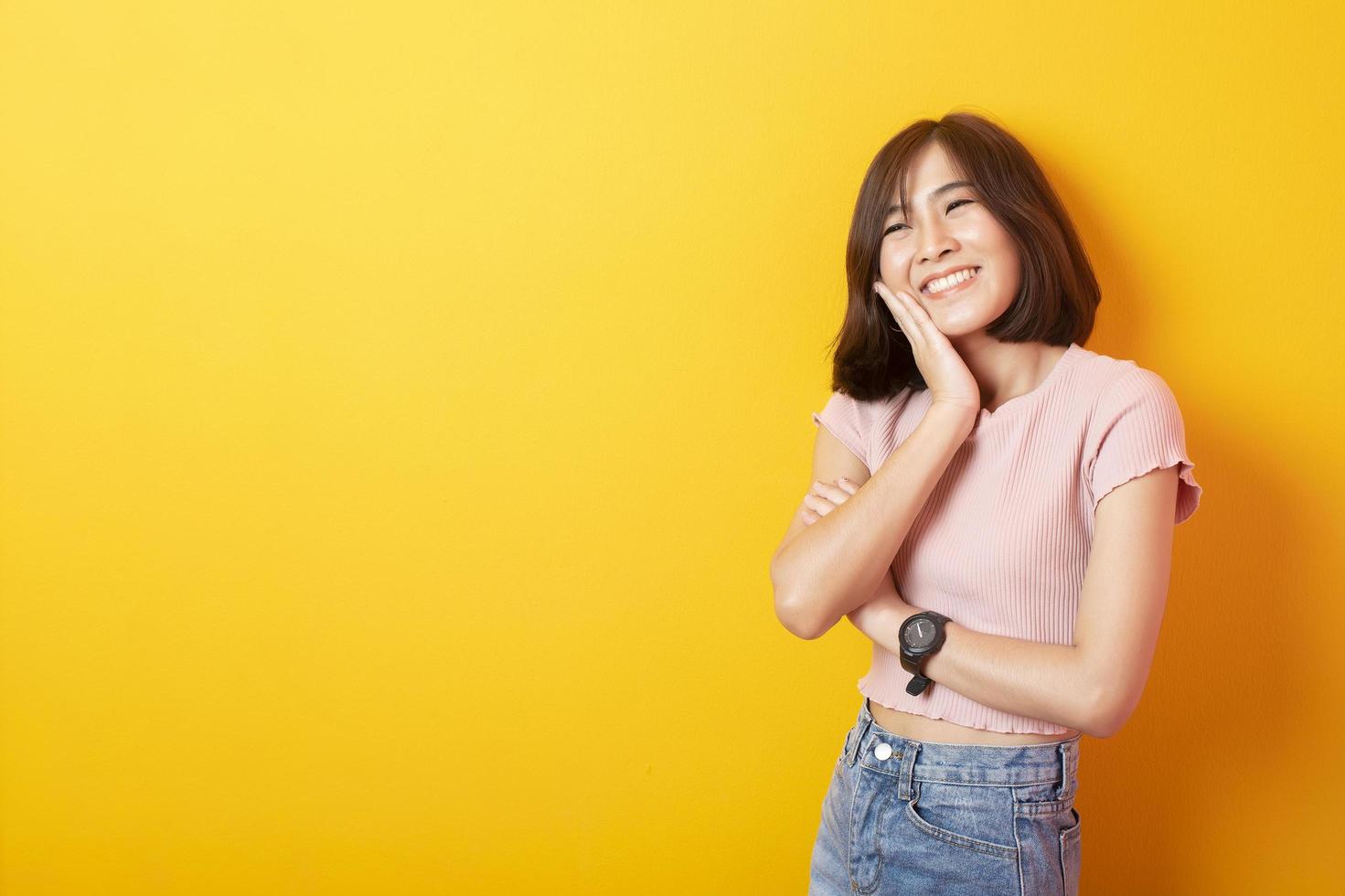 bela mulher asiática estudante universitário feliz em fundo amarelo foto