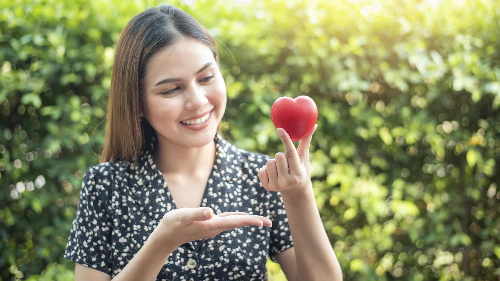 mão de mulher está segurando o conceito de coração vermelho, amor e cuidados de saúde foto