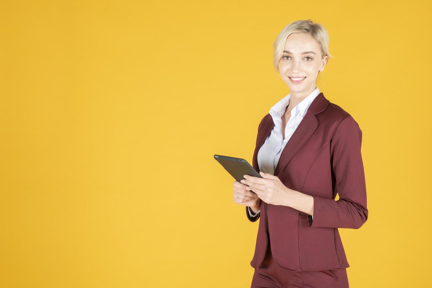 mulher de negócios está usando tablet em fundo amarelo de estúdio foto