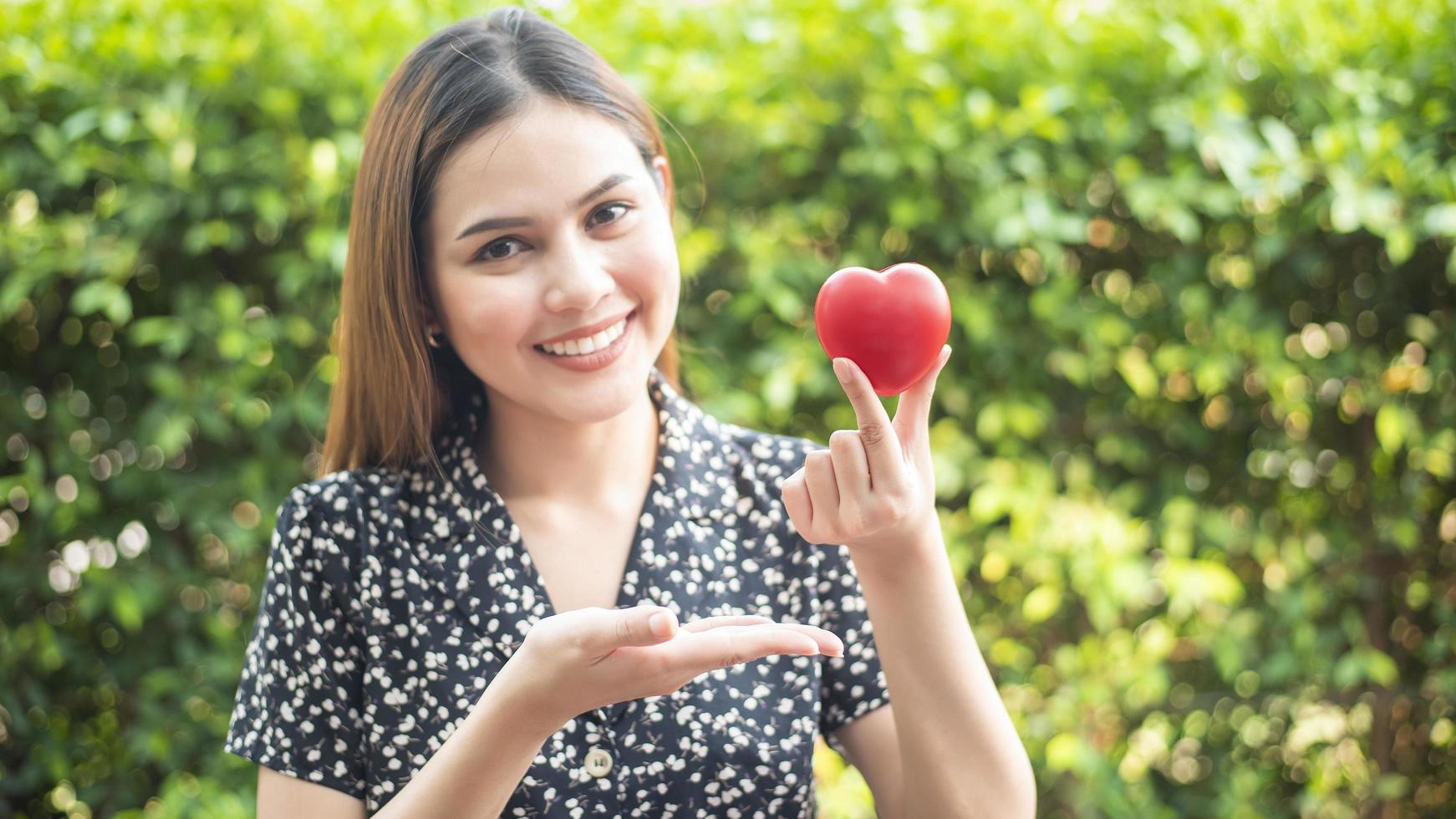 mão de mulher está segurando o conceito de coração vermelho, amor e cuidados de saúde foto