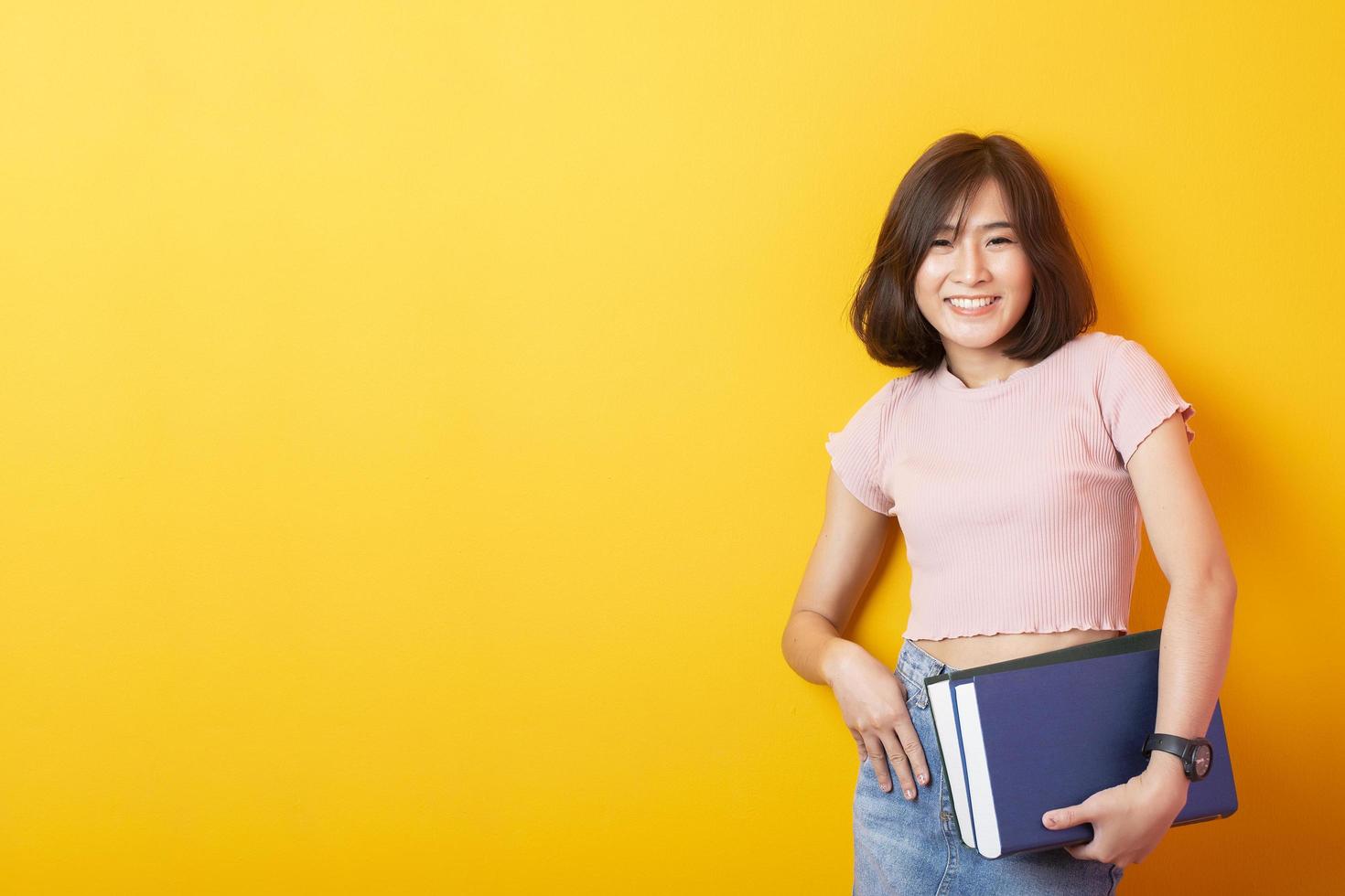 bela mulher asiática estudante universitário feliz em fundo amarelo foto