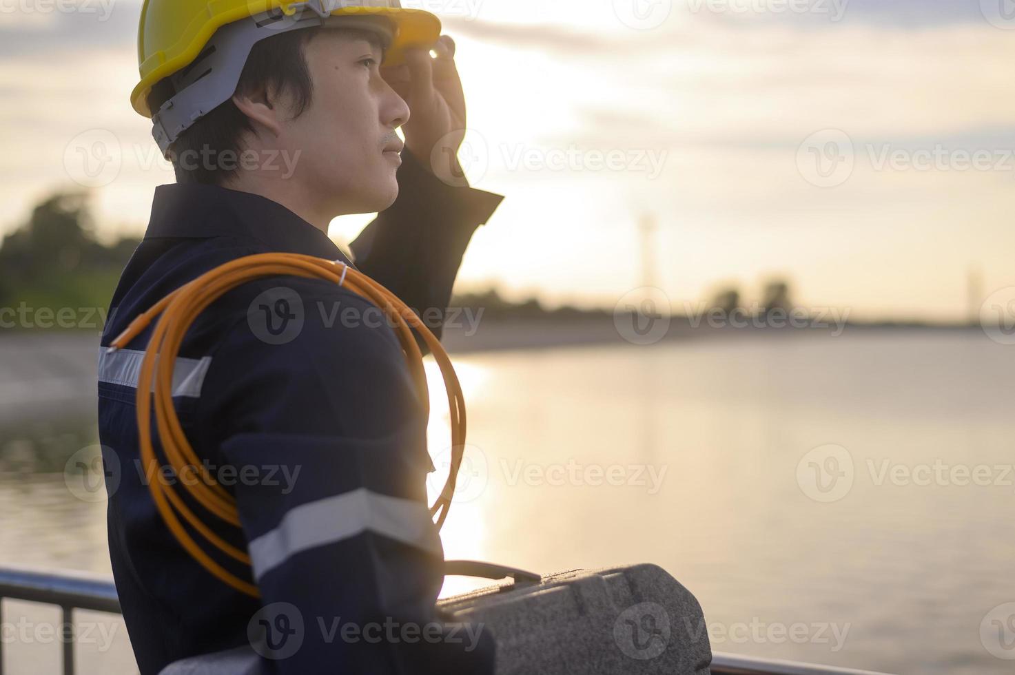 um engenheiro masculino usando um capacete protetor ao pôr do sol. foto