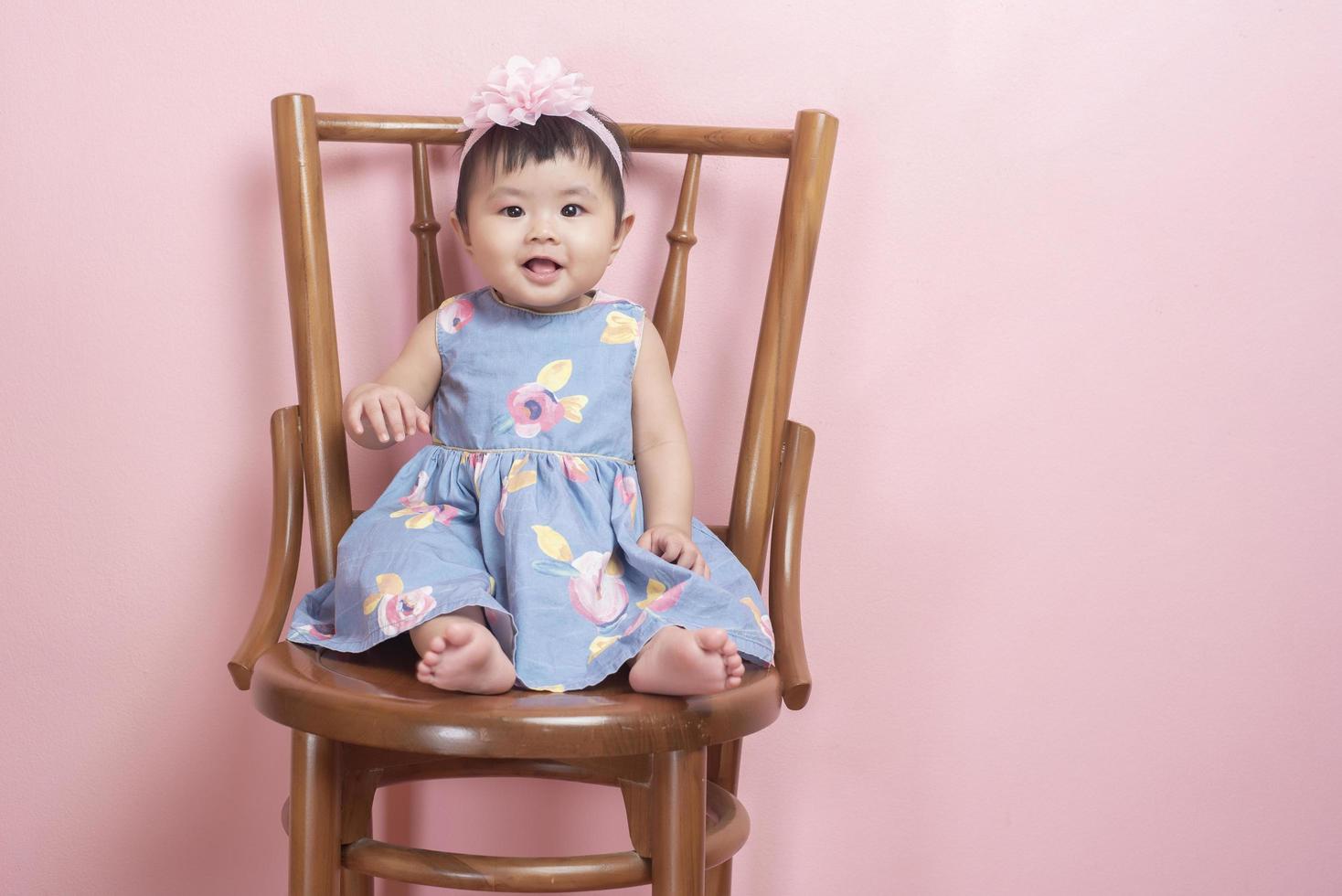 adorável menina asiática é retrato em fundo rosa foto