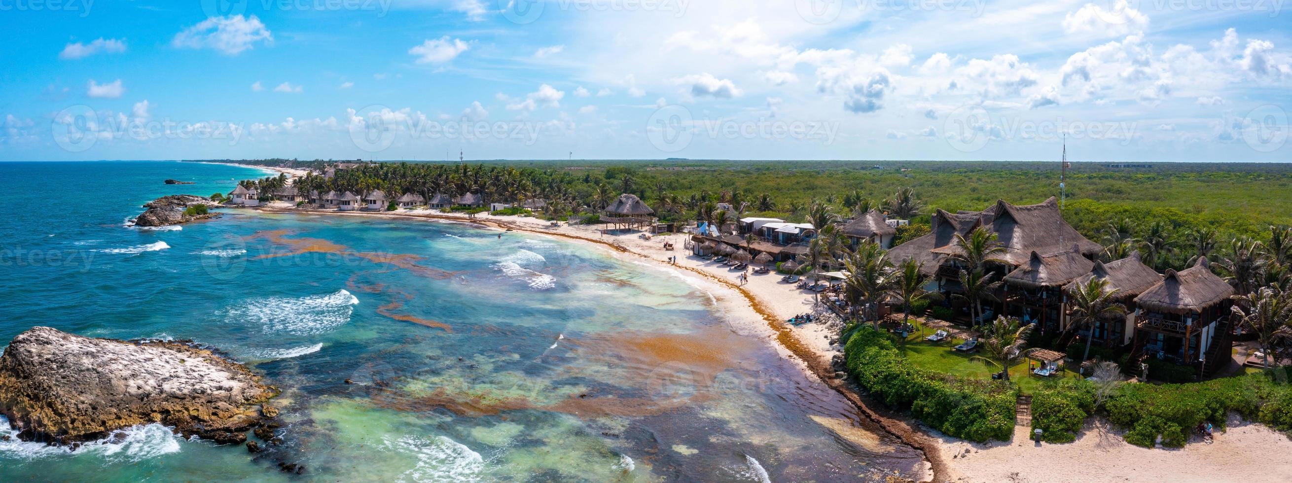 costa aérea de tulum na praia com um mar mágico do caribe e pequenas cabanas na costa. foto