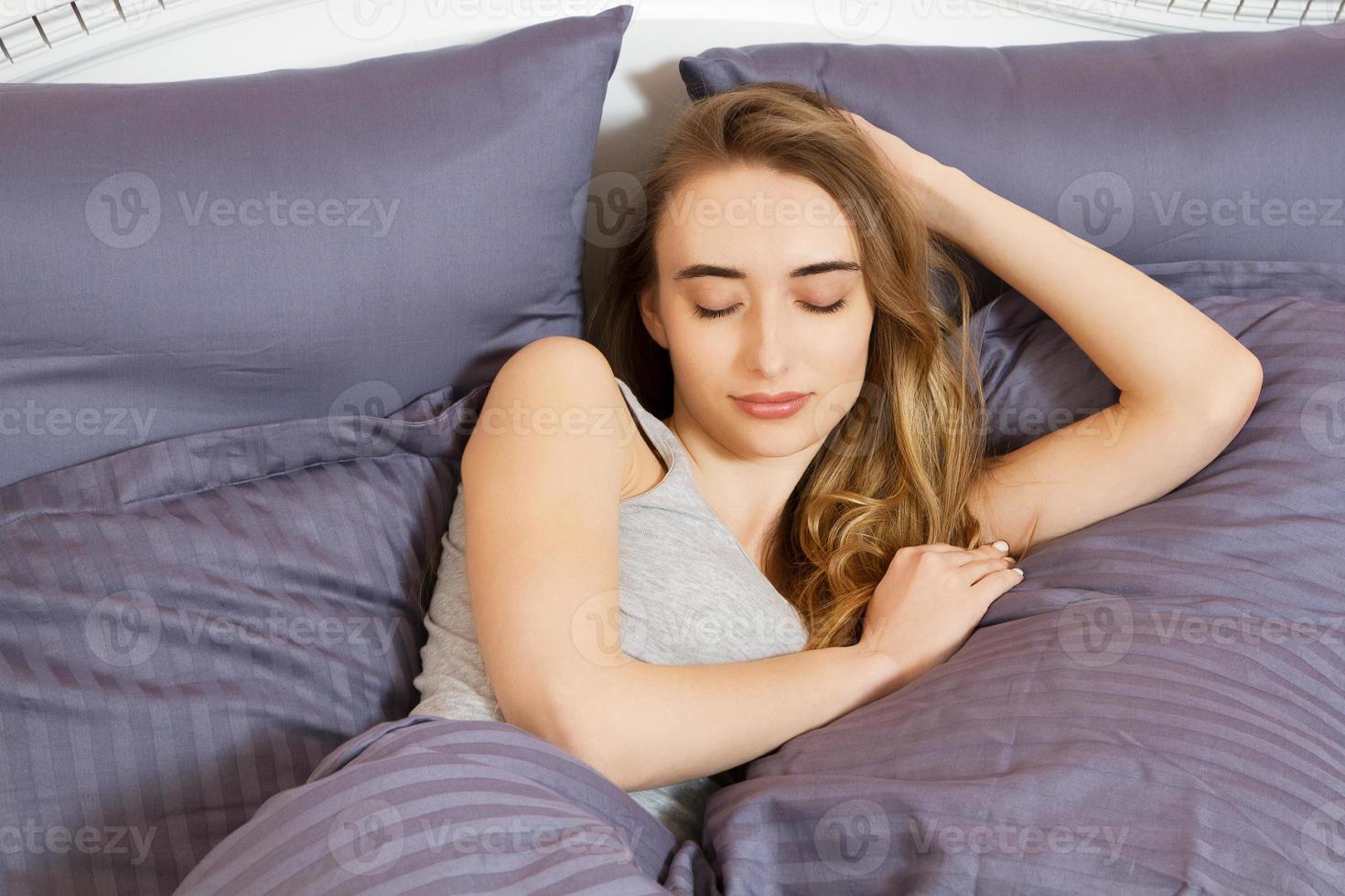 retrato de uma linda garota de sorriso na cama depois de dormir foto