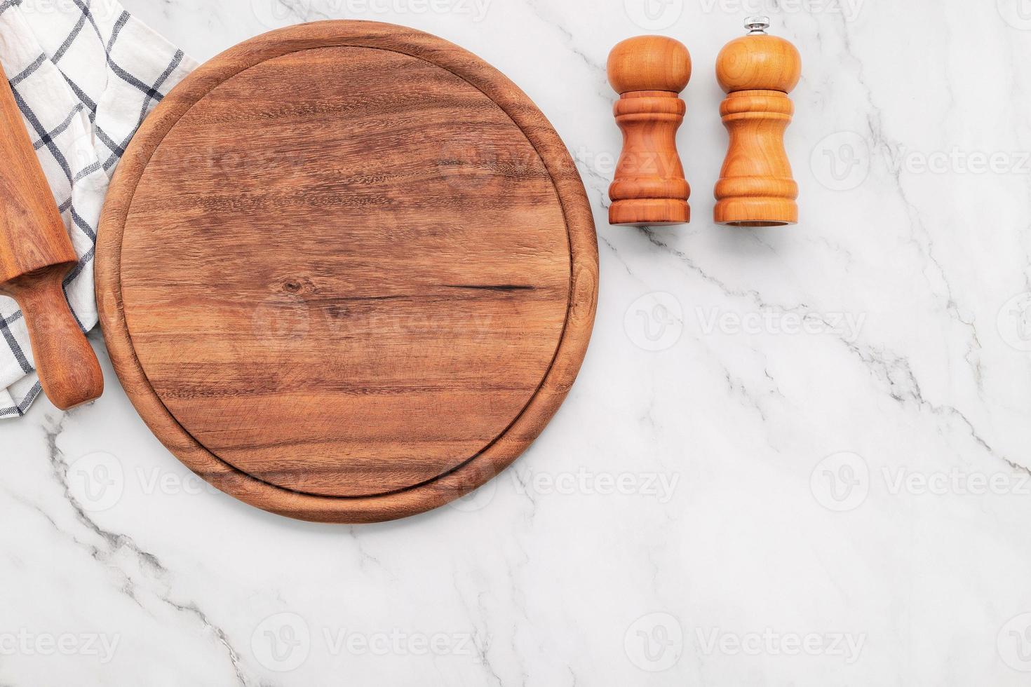 bandeja de pizza de madeira vazia com guardanapo e rolo na mesa da cozinha de pedra de mármore. placa de pizza e toalha de mesa em fundo de mármore branco. foto