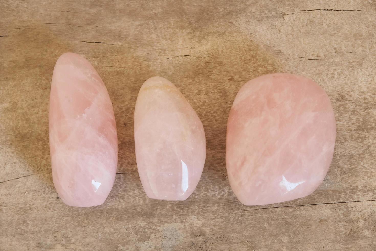 cristais polidos pedra preciosa de quartzo rosa em fundo de madeira foto