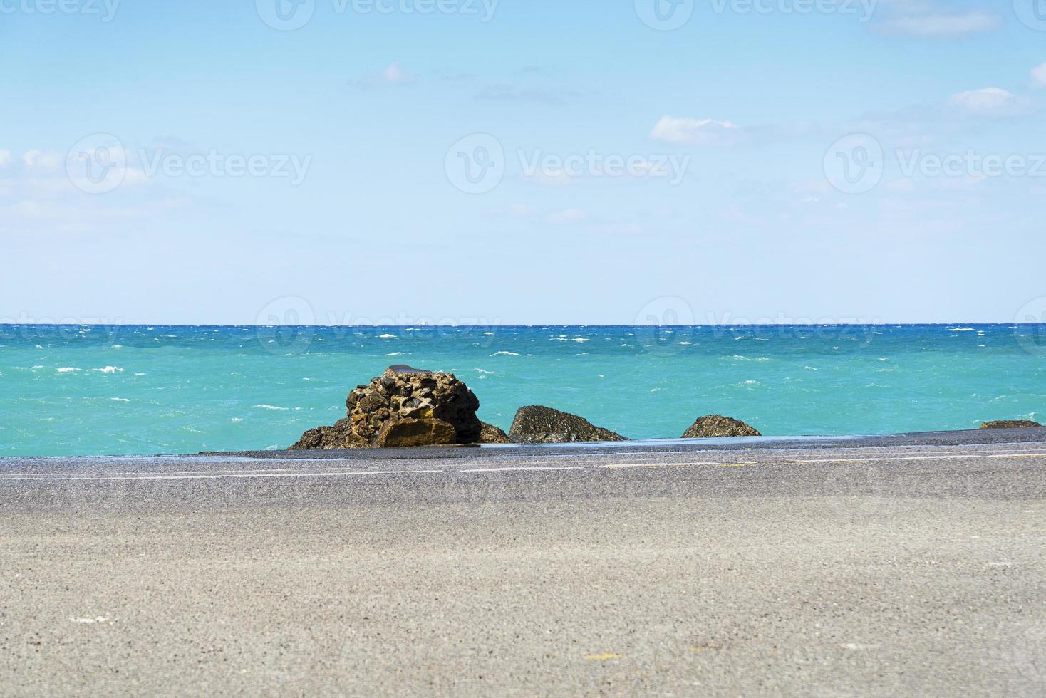 estrada de asfalto e linha de costa do mar com céu azul no horizonte. paisagem em dia ensolarado de verão foto