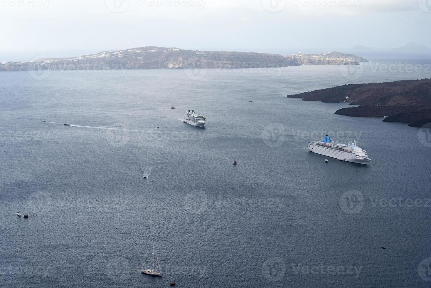 bela paisagem com vista para o mar. navio de cruzeiro no mar perto de nea kameni, uma pequena ilha grega no mar egeu perto de santorini. foto