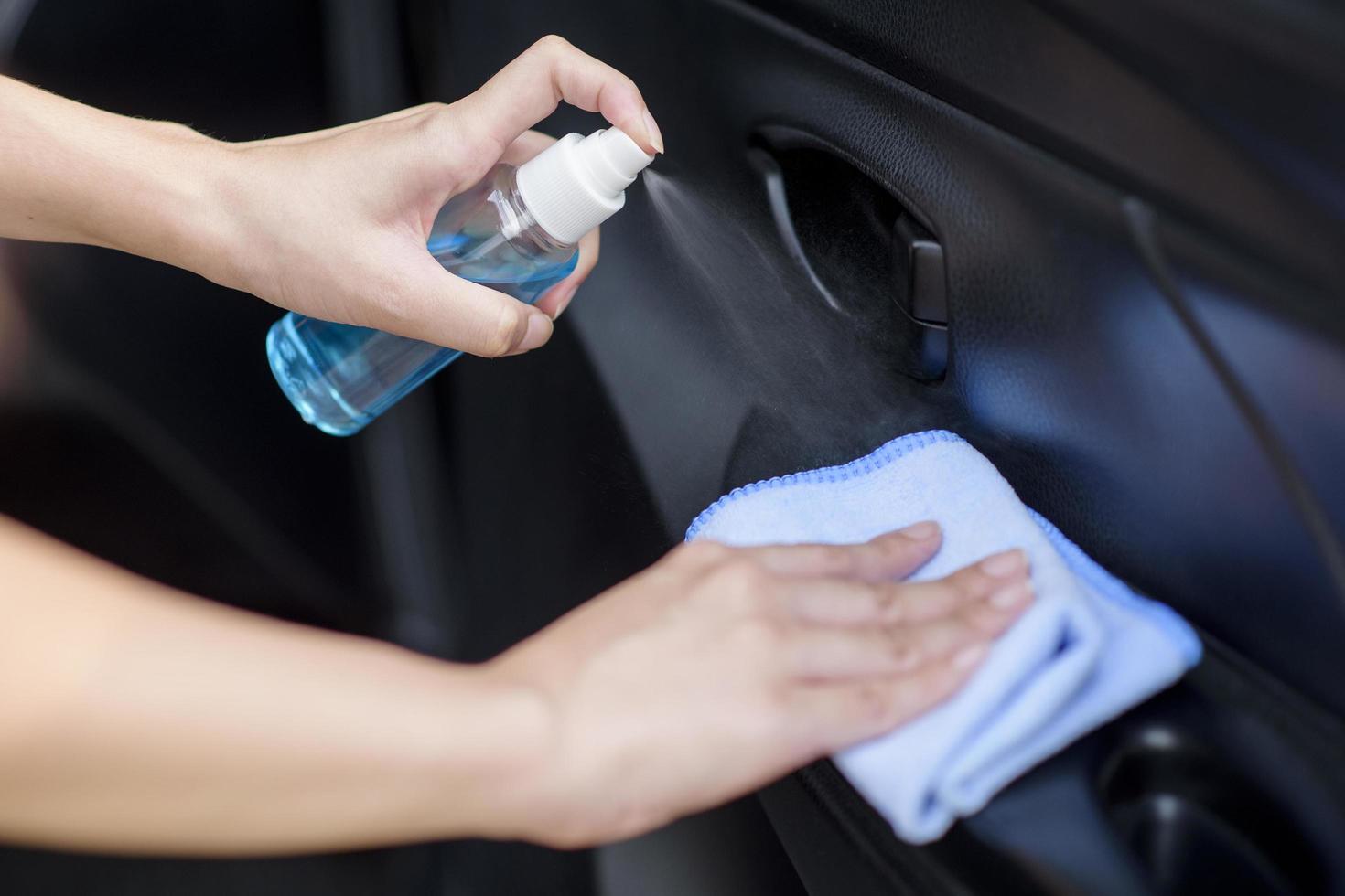 close-up da mão da mulher está limpando o carro por spray de álcool foto