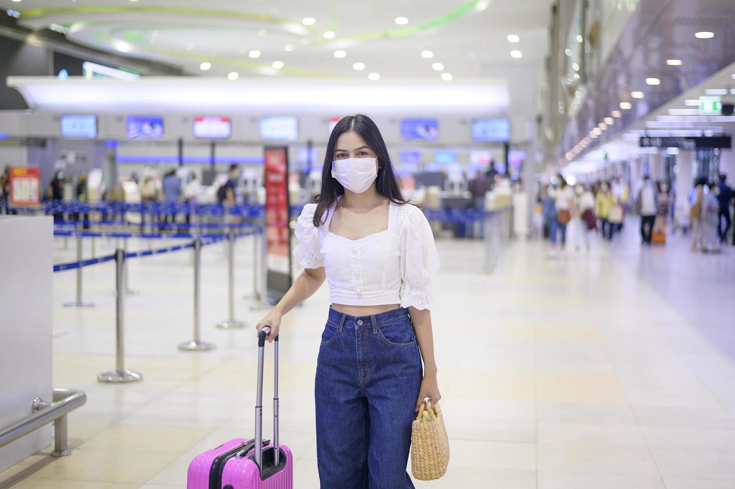 uma mulher viajante está usando máscara protetora no aeroporto internacional, viaja sob pandemia covid-19, viagens de segurança, protocolo de distanciamento social, novo conceito de viagem normal foto