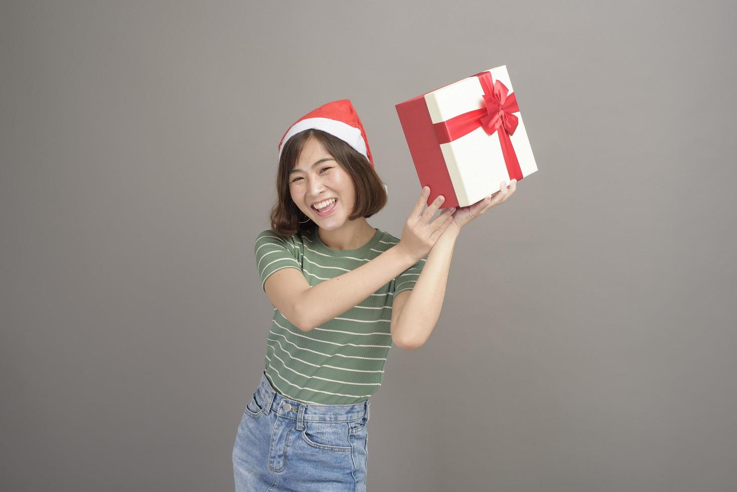 retrato de mulher bonita com chapéu de papai noel vermelho segurando a caixa de presente sobre fundo de estúdio, natal e ano novo conceito foto