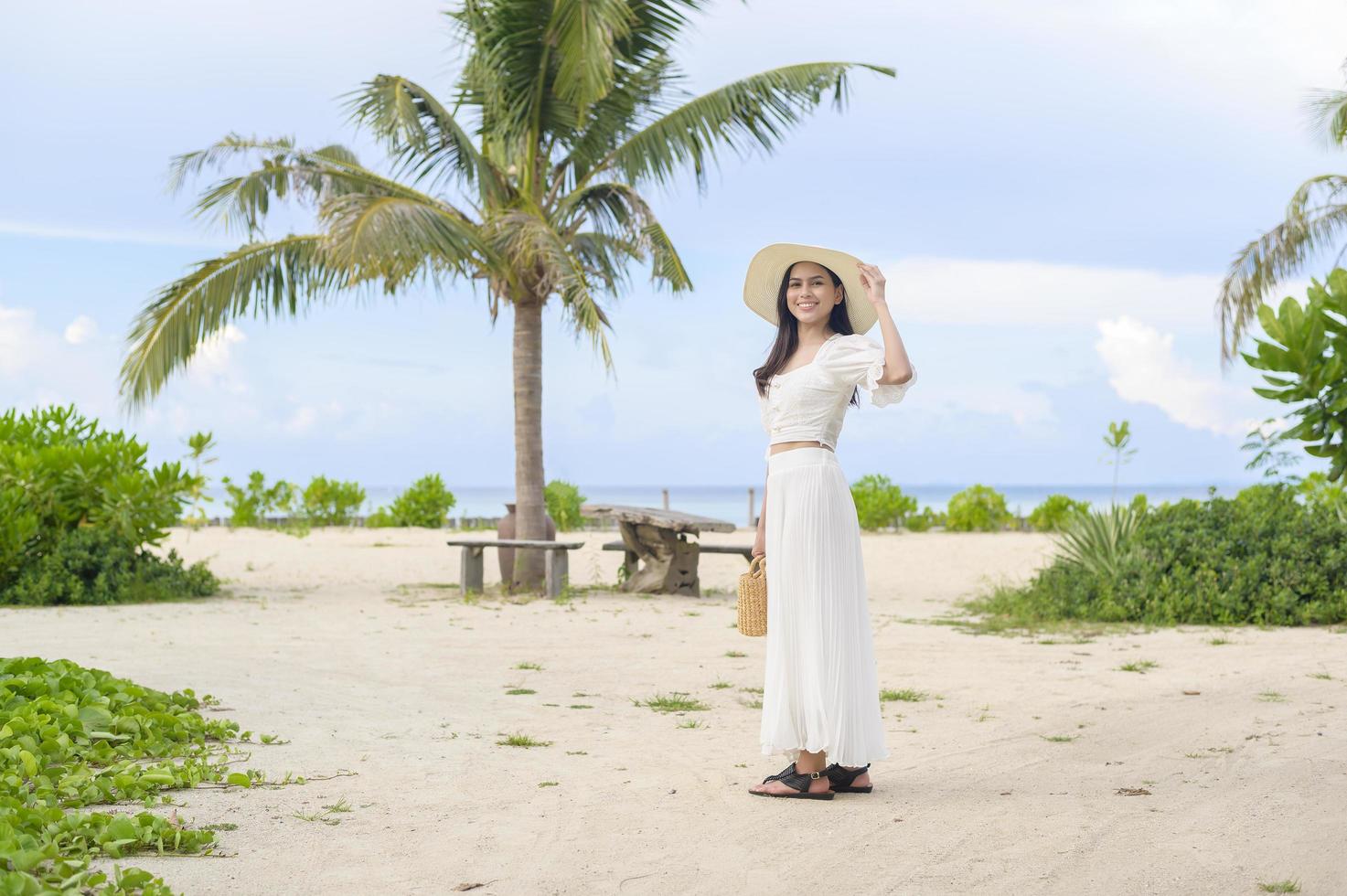 uma mulher bonita feliz no vestido branco curtindo e relaxando no conceito de praia, verão e férias foto