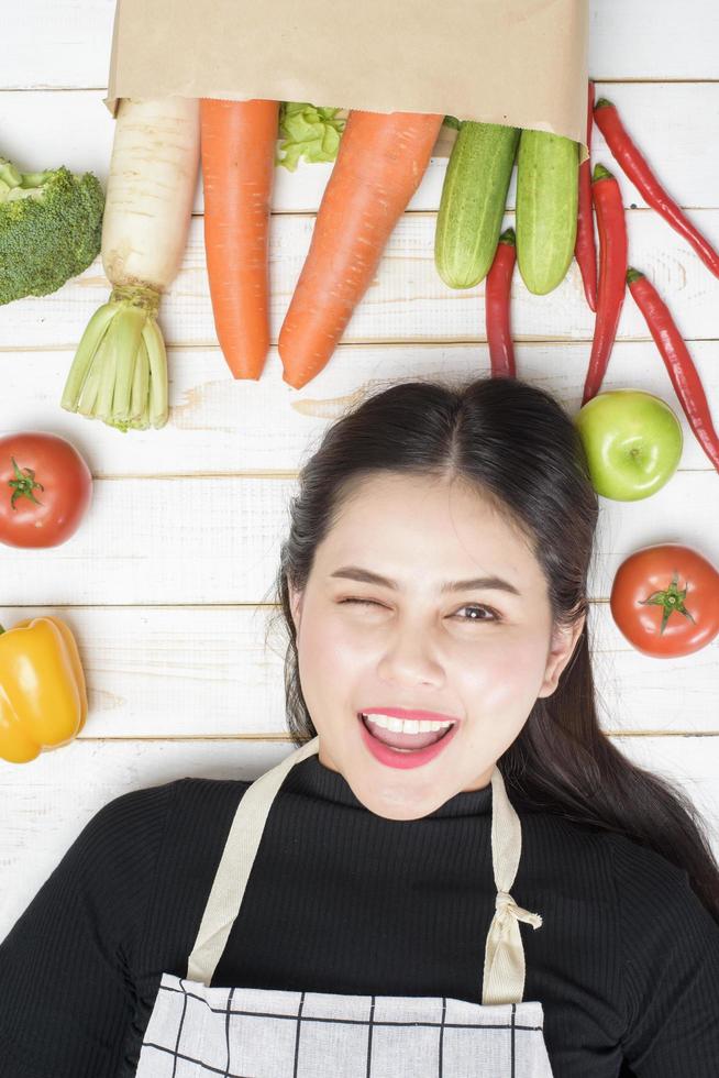 mulher com legumes na sacola de compras no fundo branco de madeira foto